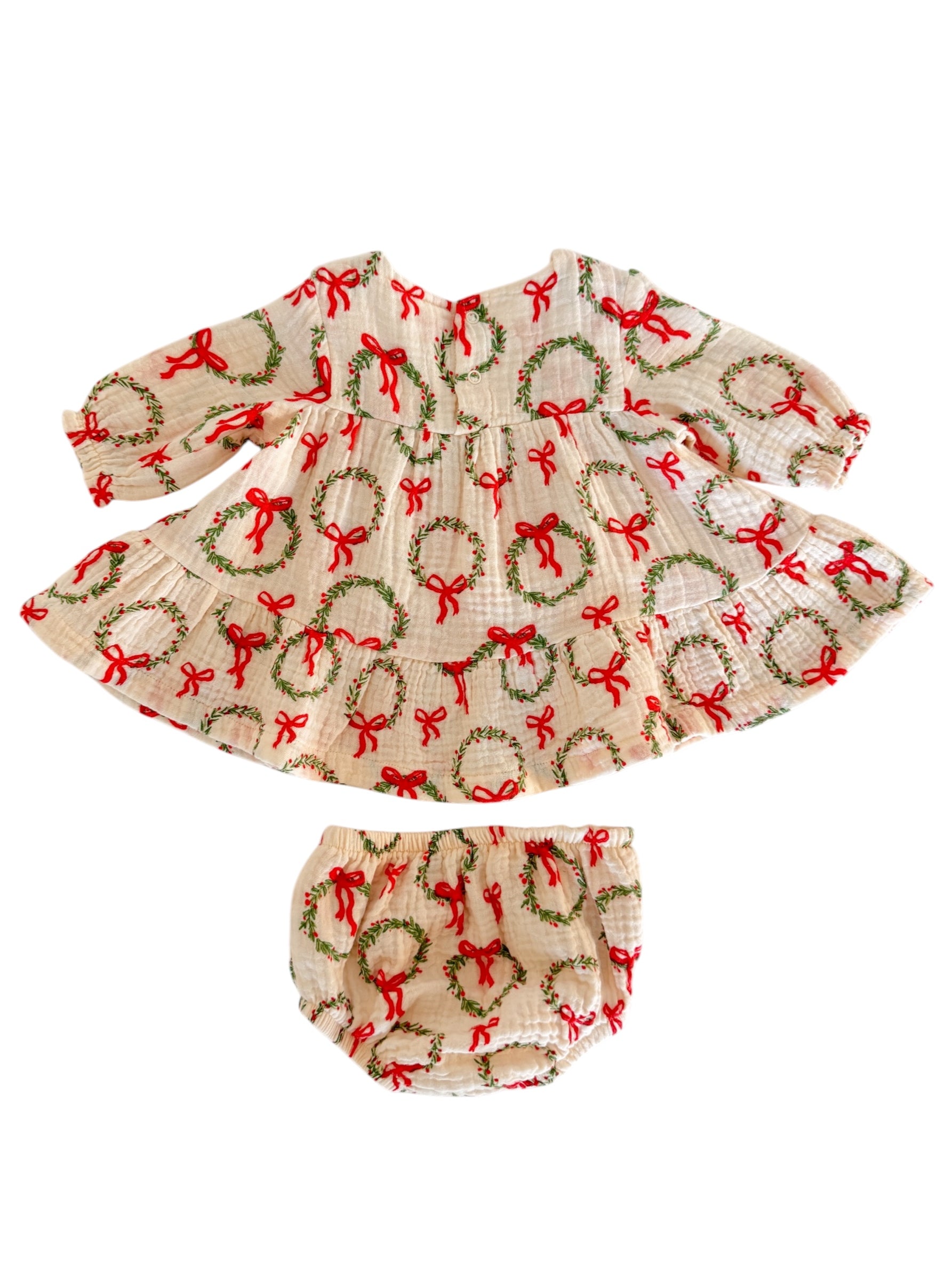 Girl's holiday dress and bloomer set featuring wreath and bow patterns on a cream background.