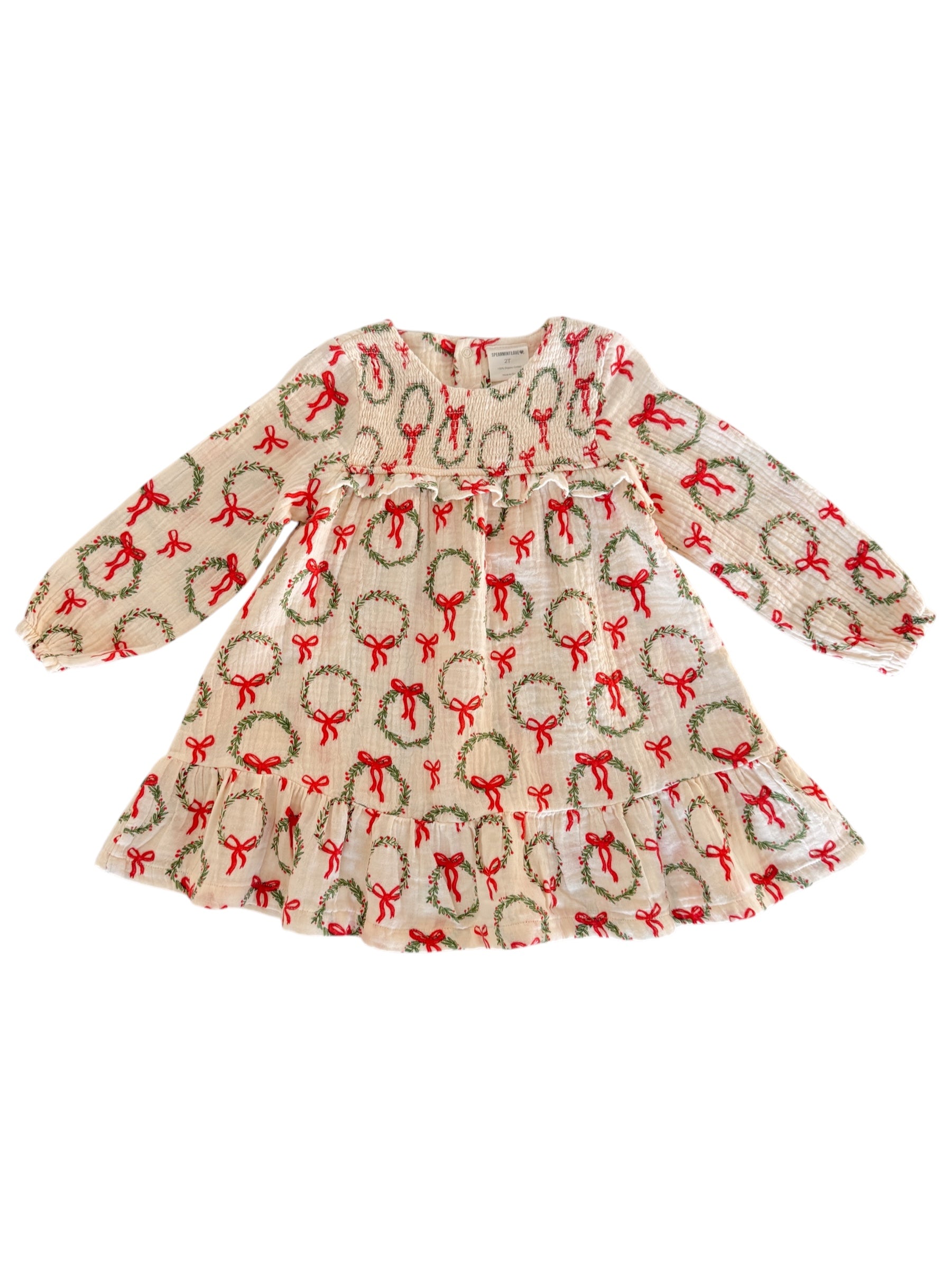 Cream dress with festive wreath and bow pattern, featuring long sleeves and a flared skirt. Perfect for holiday occasions.