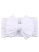 White headband with a large bow, featuring soft textured fabric and a stretchy band.