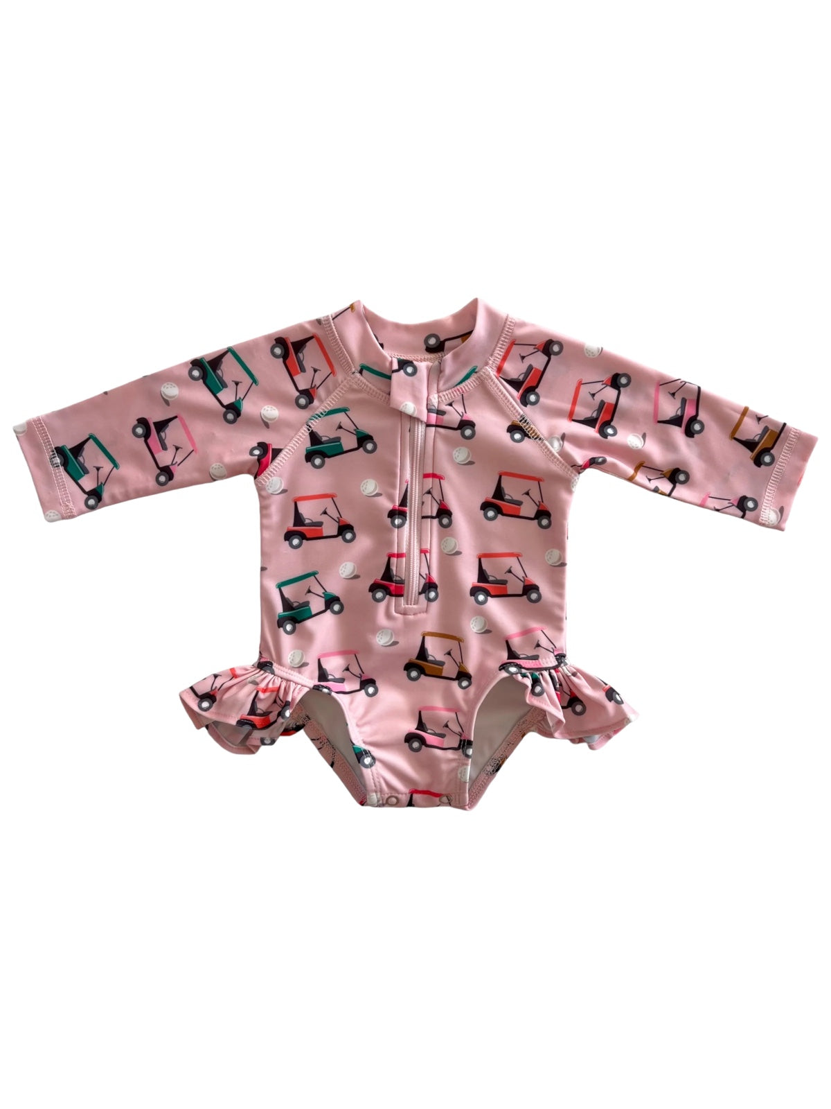 Pink children's swimsuit with golf cart print and ruffled edges, featuring long sleeves and a zipper.