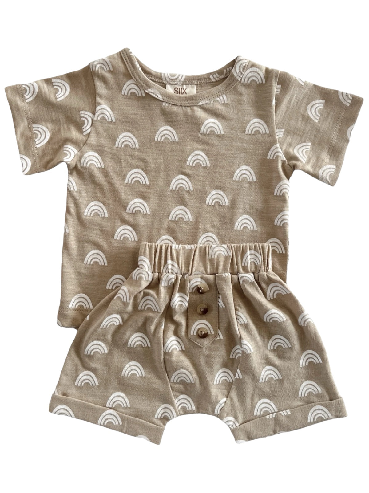 Beige toddler outfit with white rainbow patterns, featuring a short-sleeved top and matching shorts with buttons.