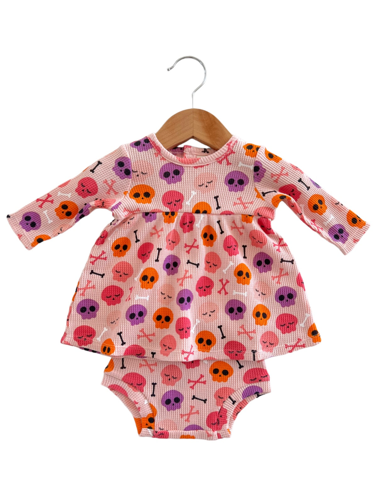 Pink toddler dress with skull and crossbones pattern, featuring long sleeves and matching bottoms.