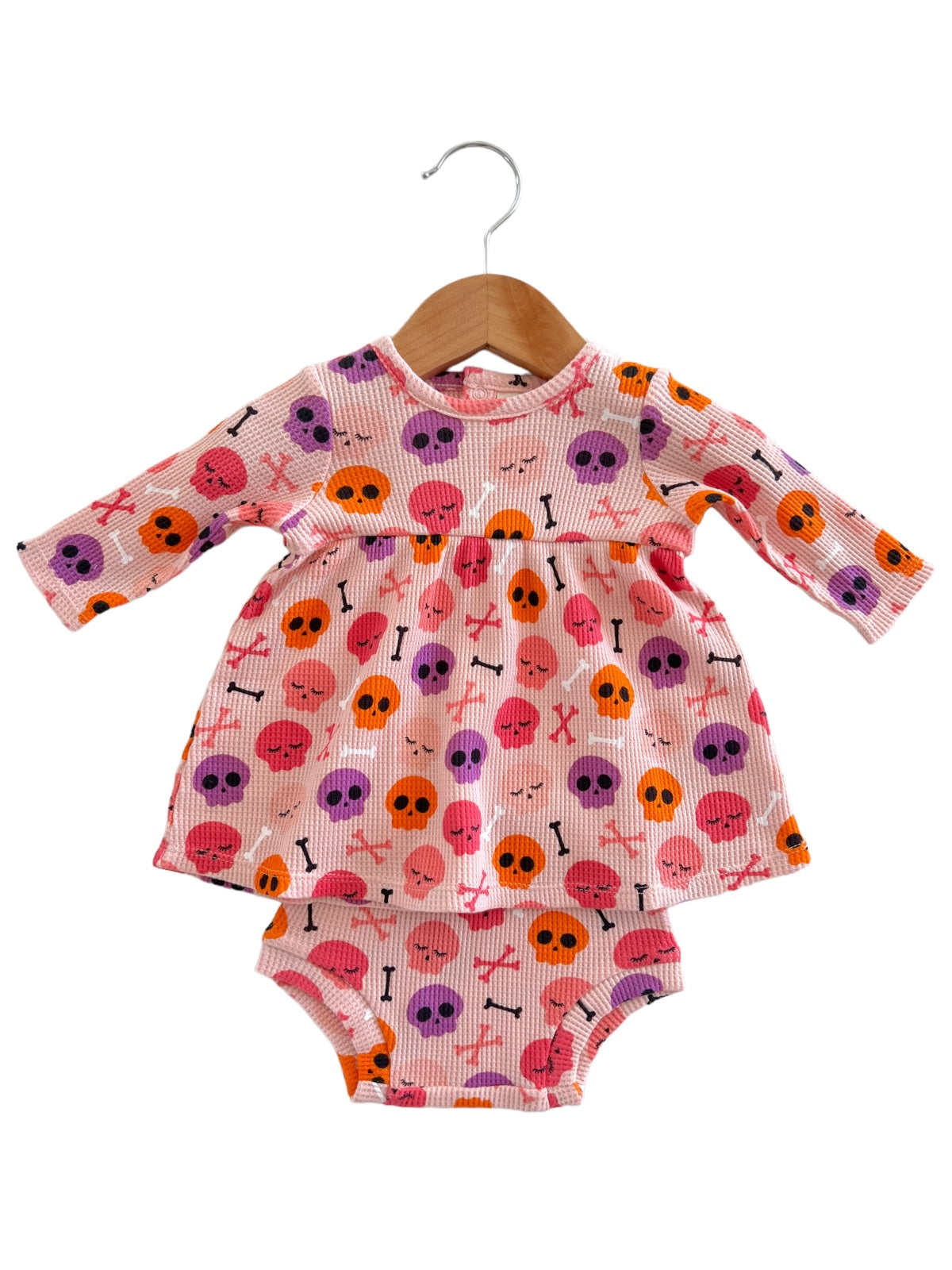 Pink toddler dress with skull and crossbones pattern, featuring long sleeves and matching bottoms.