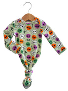 Long-sleeve baby onesie with colorful skull and crossbones print, hanging on a wooden hanger.