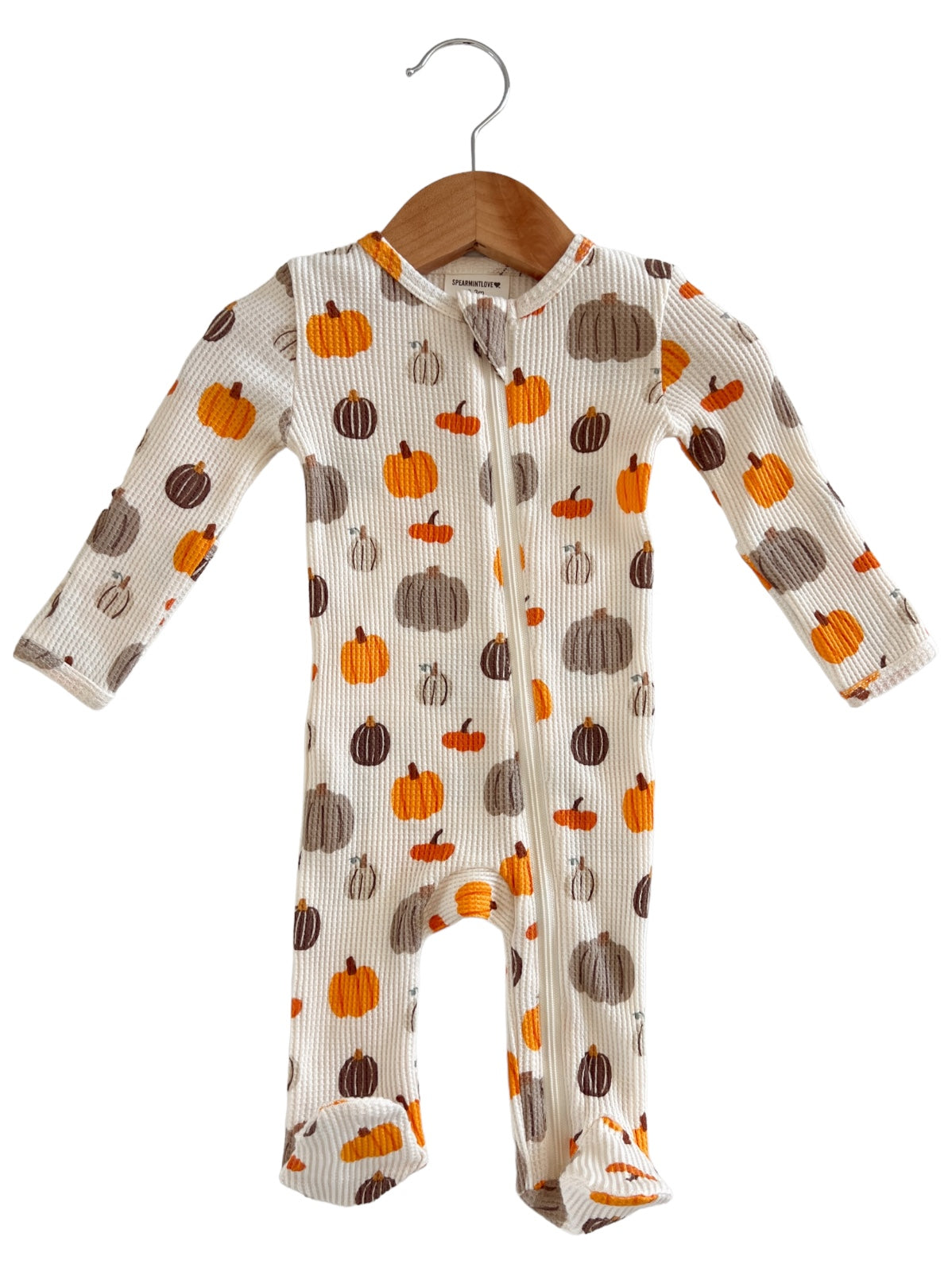 Cute baby onesie with colorful pumpkin prints, hanging on a wooden hanger against a white background.