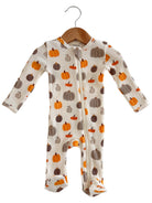 Cute baby onesie with colorful pumpkin prints, hanging on a wooden hanger against a white background.