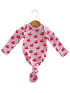 Long-sleeve baby outfit with a pink cupcake pattern, hanging on a wooden hanger.