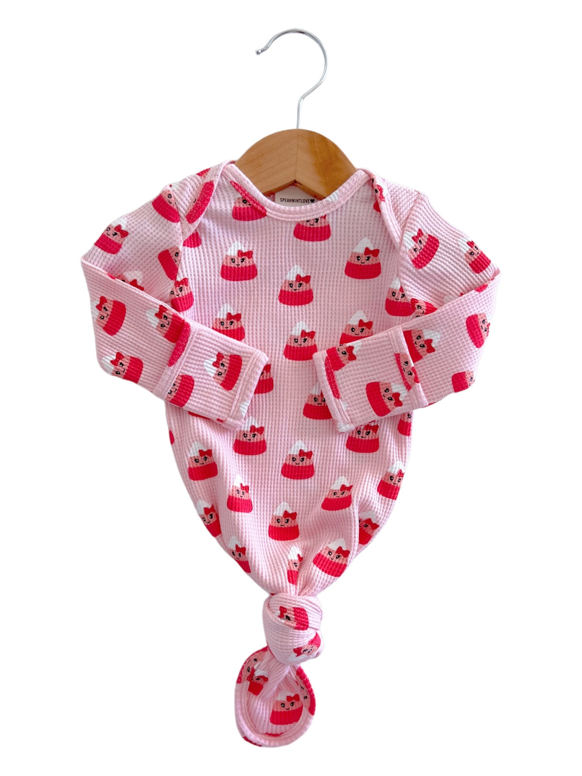 Pink baby sleeper with cute fox print, tied at the bottom, hanging on a wooden hanger.