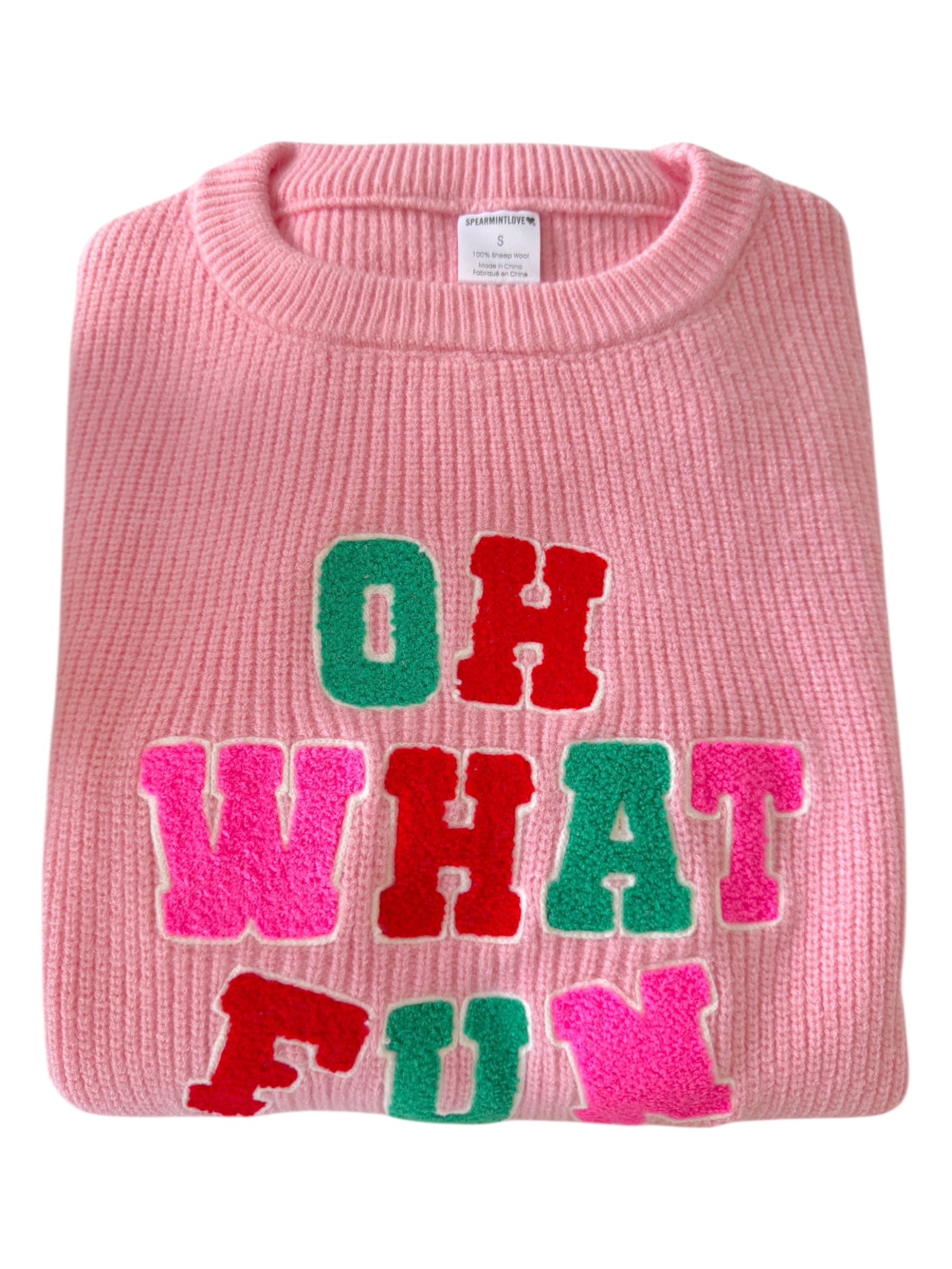 Pink sweater with colorful letters spelling "OH WHAT FUN" in red, green, and pink.