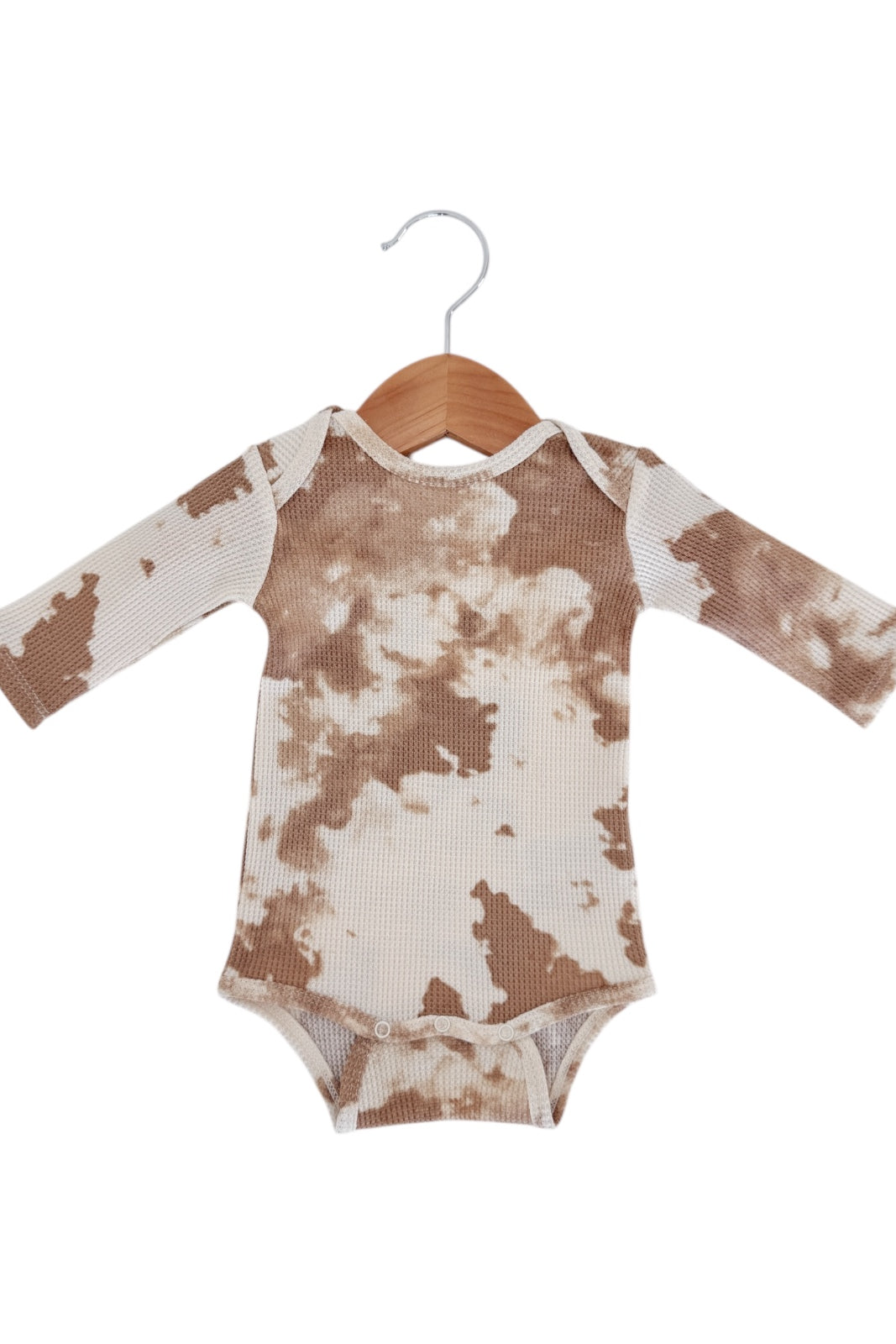 Brown and cream tie-dye long-sleeve onesie displayed on a wooden hanger.