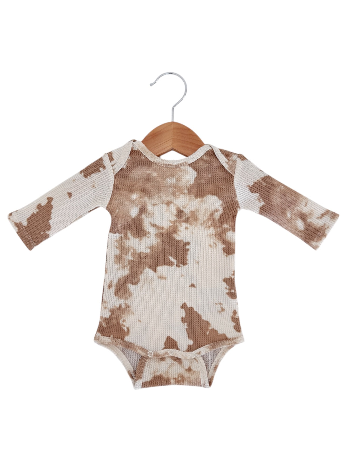 Brown and cream tie-dye long-sleeve onesie displayed on a wooden hanger.