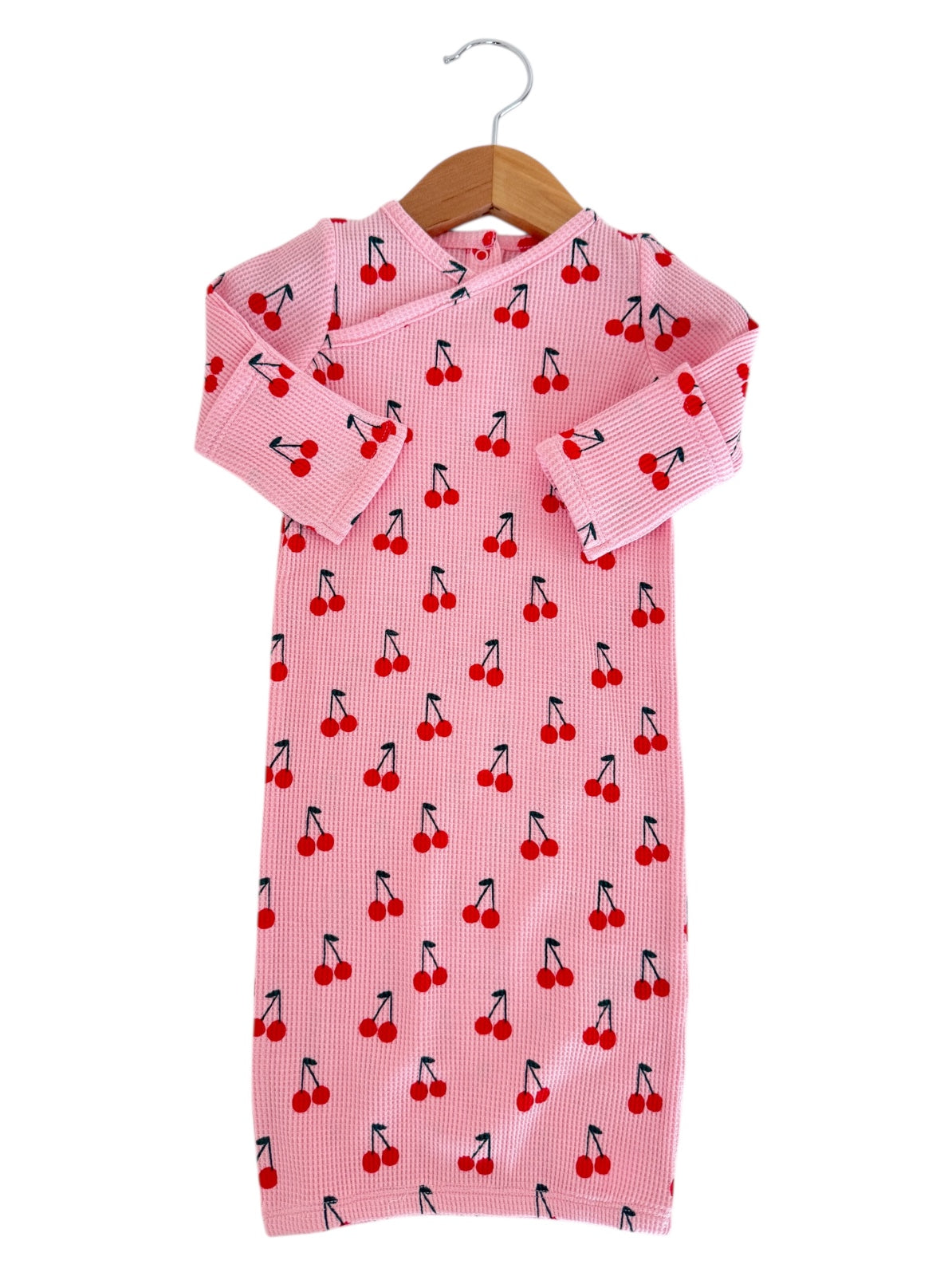 Pink children's dress with cherry print, featuring long sleeves and a hanging loop. Suitable for casual wear.