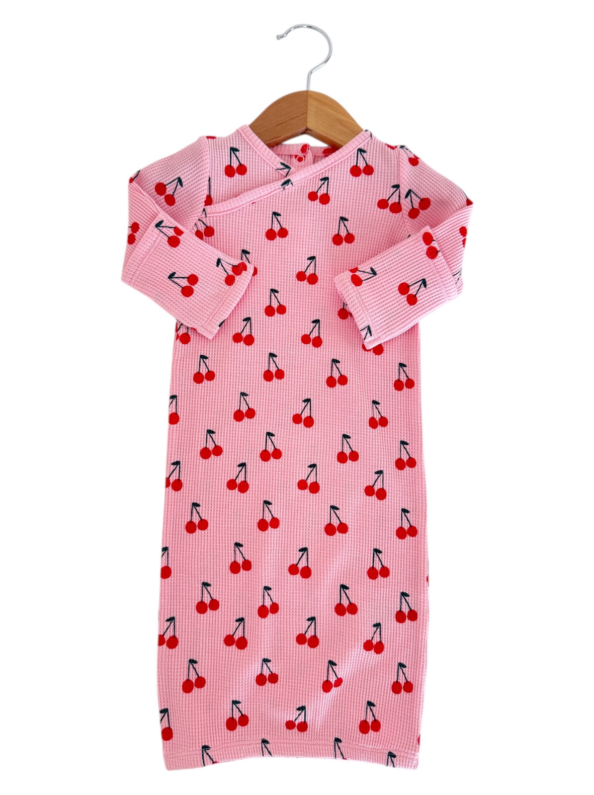 Pink children's dress with cherry print, featuring long sleeves and a hanging loop. Suitable for casual wear.