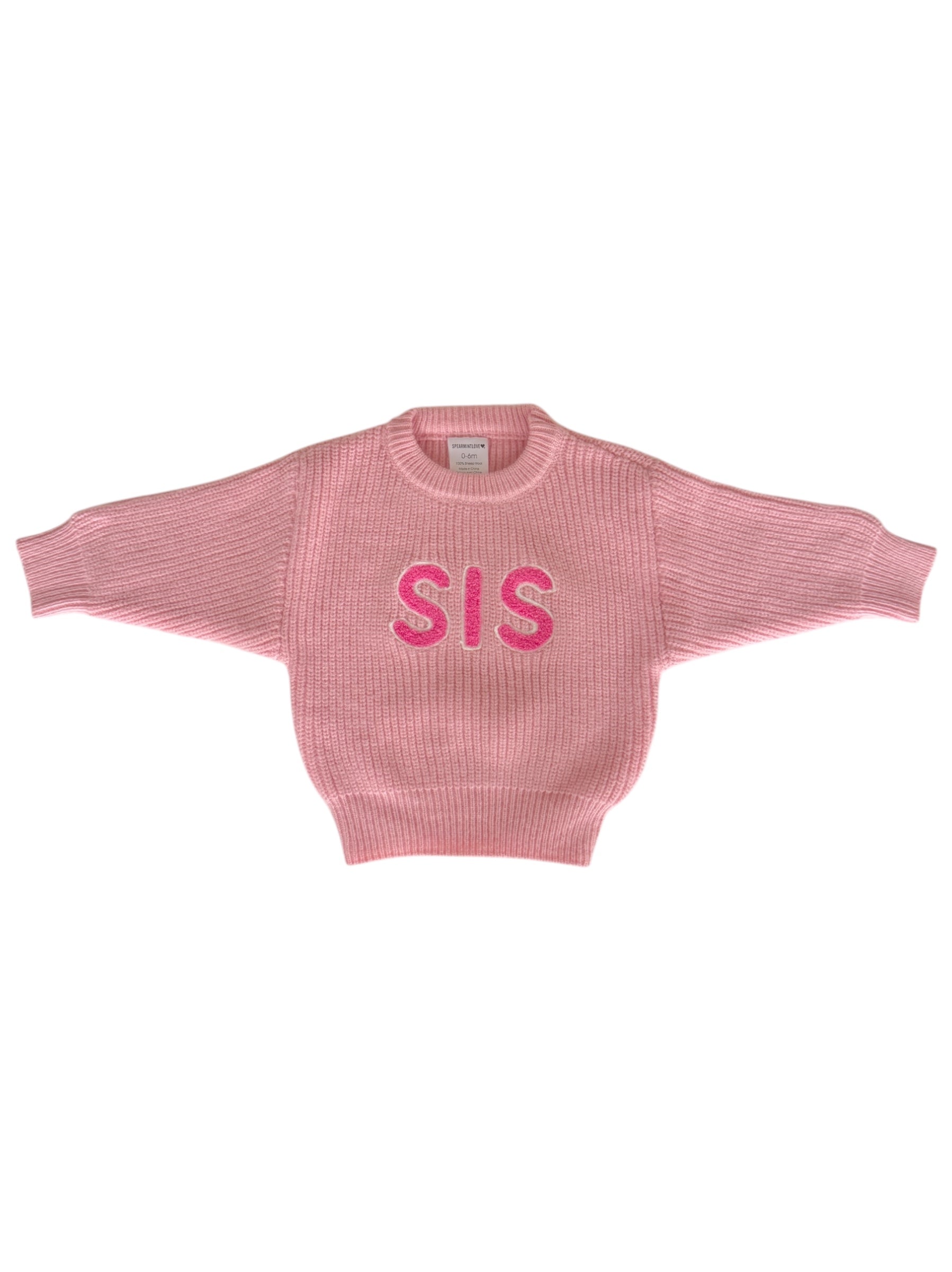 Pink knitted sweater with "SIS" printed across the front, featuring wide sleeves and a ribbed collar.