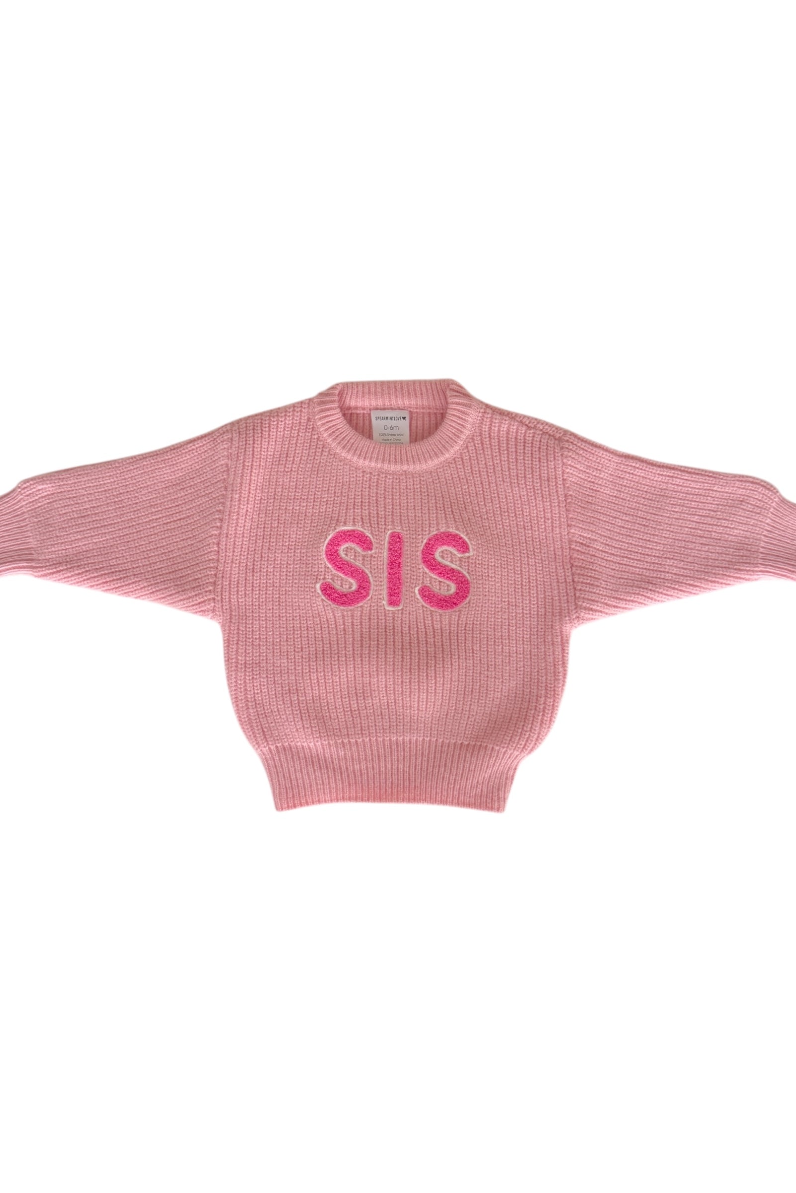 Pink knitted sweater with "SIS" printed across the front, featuring wide sleeves and a ribbed collar.