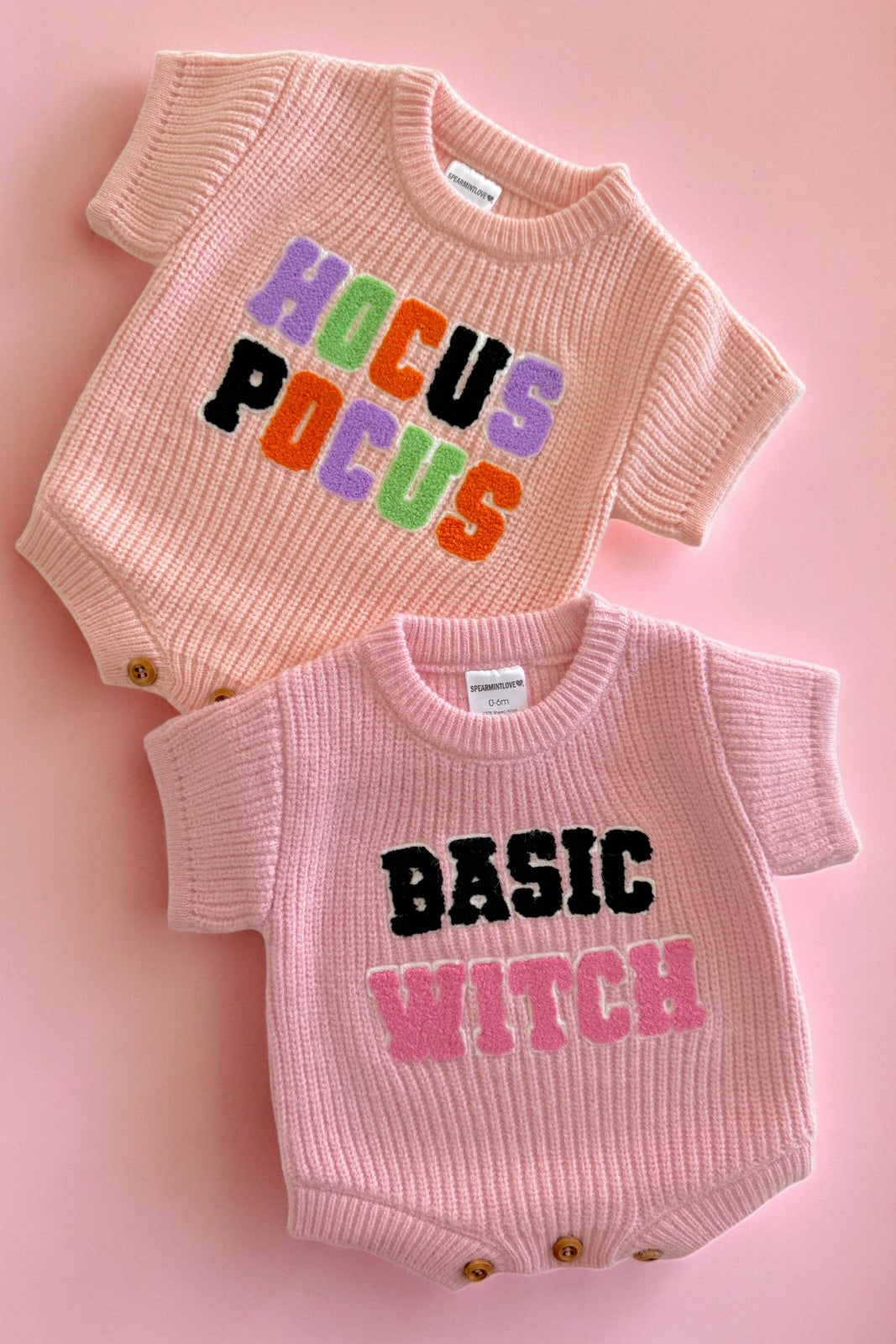 Two pink baby outfits with graphic text: "Hocus Pocus" on top and "Basic Witch" on the bottom, set against a pink background.