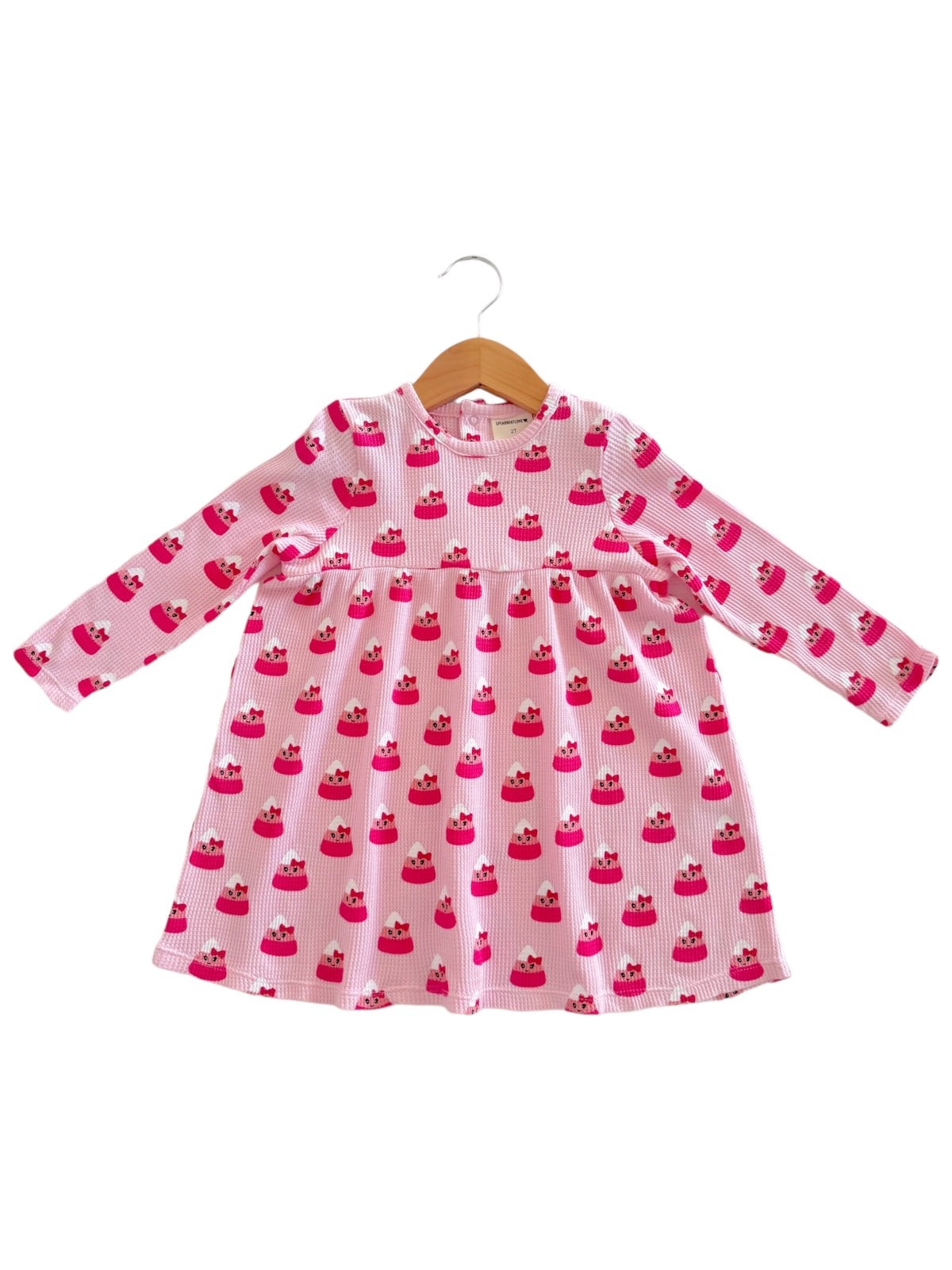 Pink long-sleeve dress with cupcake pattern on a wooden hanger.