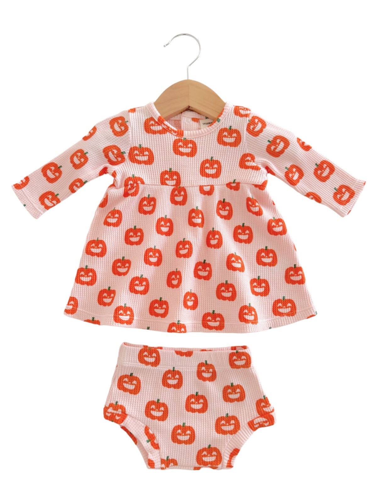 Pink children's outfit with pumpkin pattern, featuring a long-sleeve dress and matching shorts.