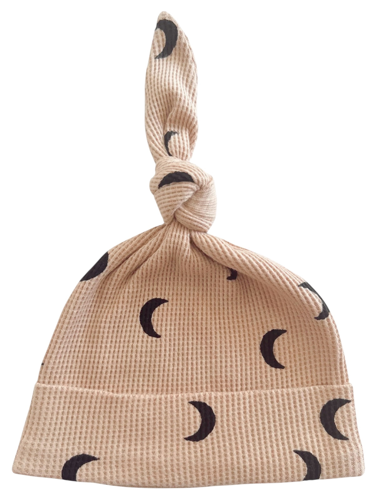 Beige baby hat with a knot on top, featuring black crescent moon patterns.