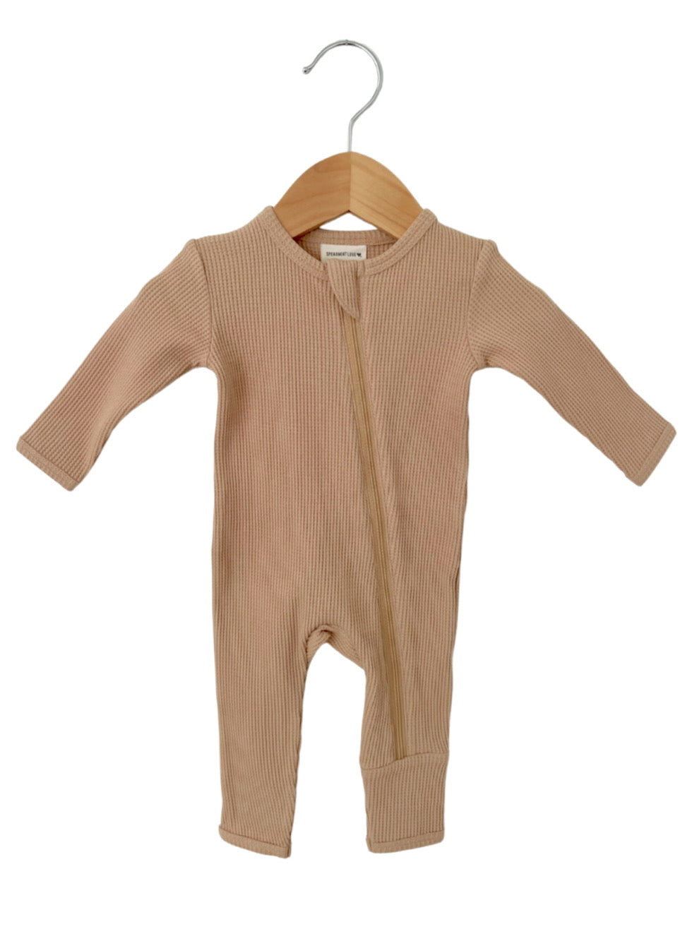 Beige ribbed infant jumpsuit hanging on a wooden hanger against a white background.