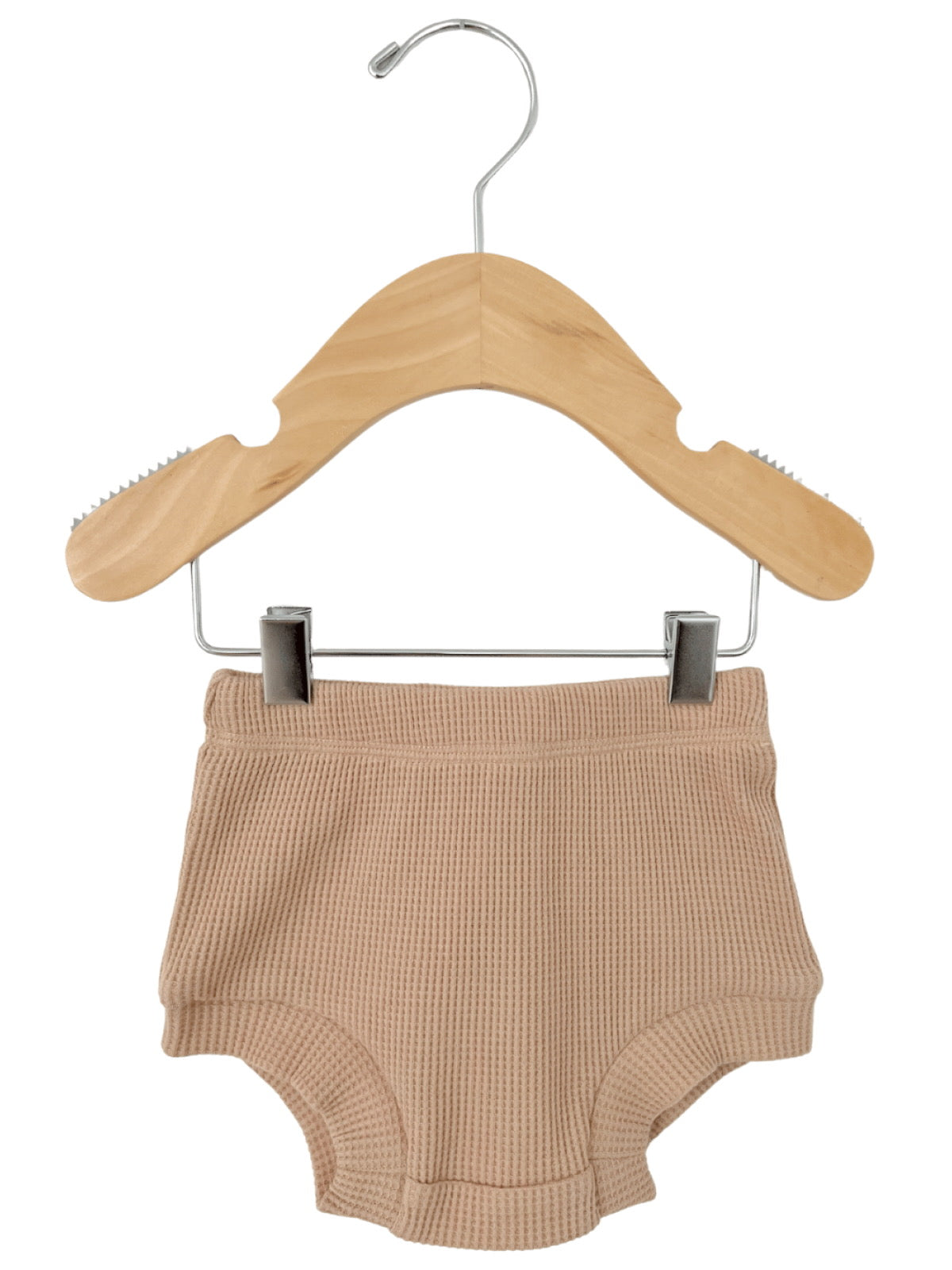 Beige waffle-knit shorts hanging on a wooden hanger against a white background.