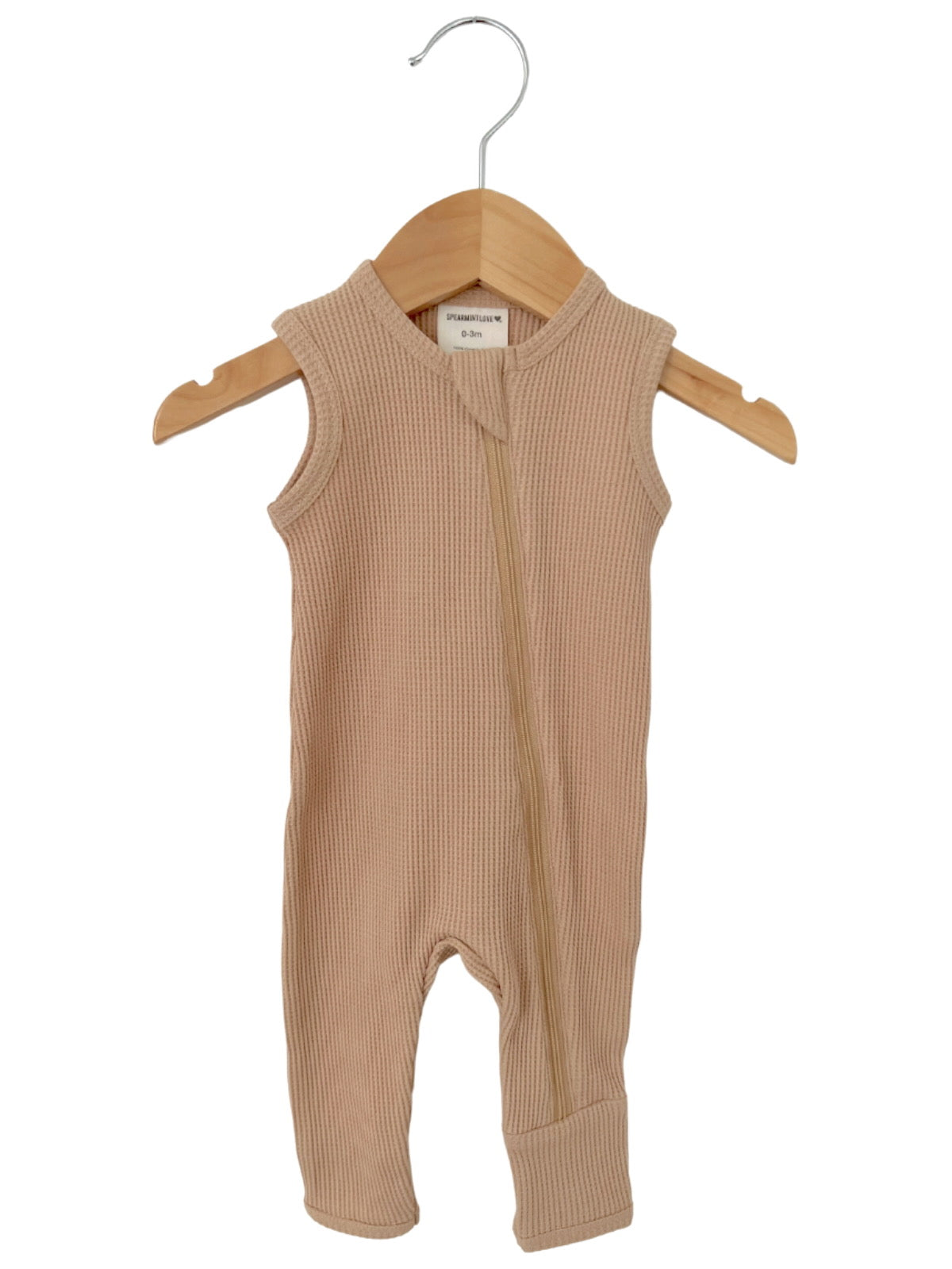 Tan ribbed baby onesie with a front zipper, displayed on a wooden hanger against a white background.