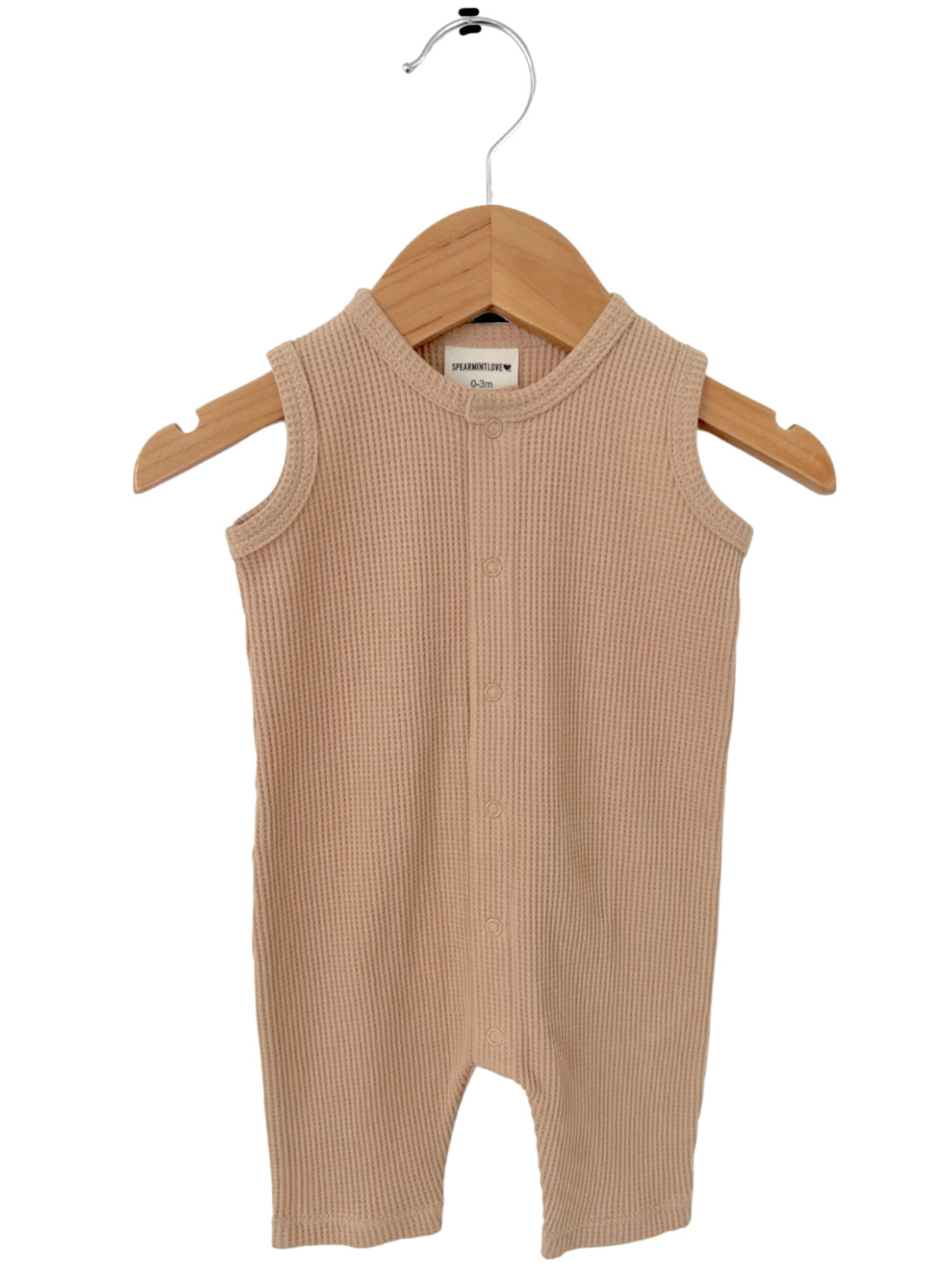 Beige sleeveless baby romper on a wooden hanger, featuring a ribbed texture and button closure.
