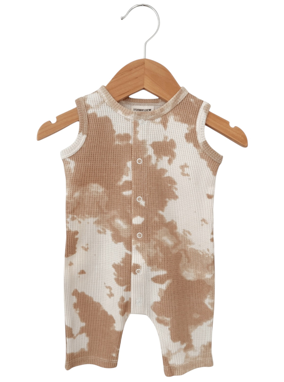 Tan and white tie-dye toddler romper hanging on a wooden hanger.