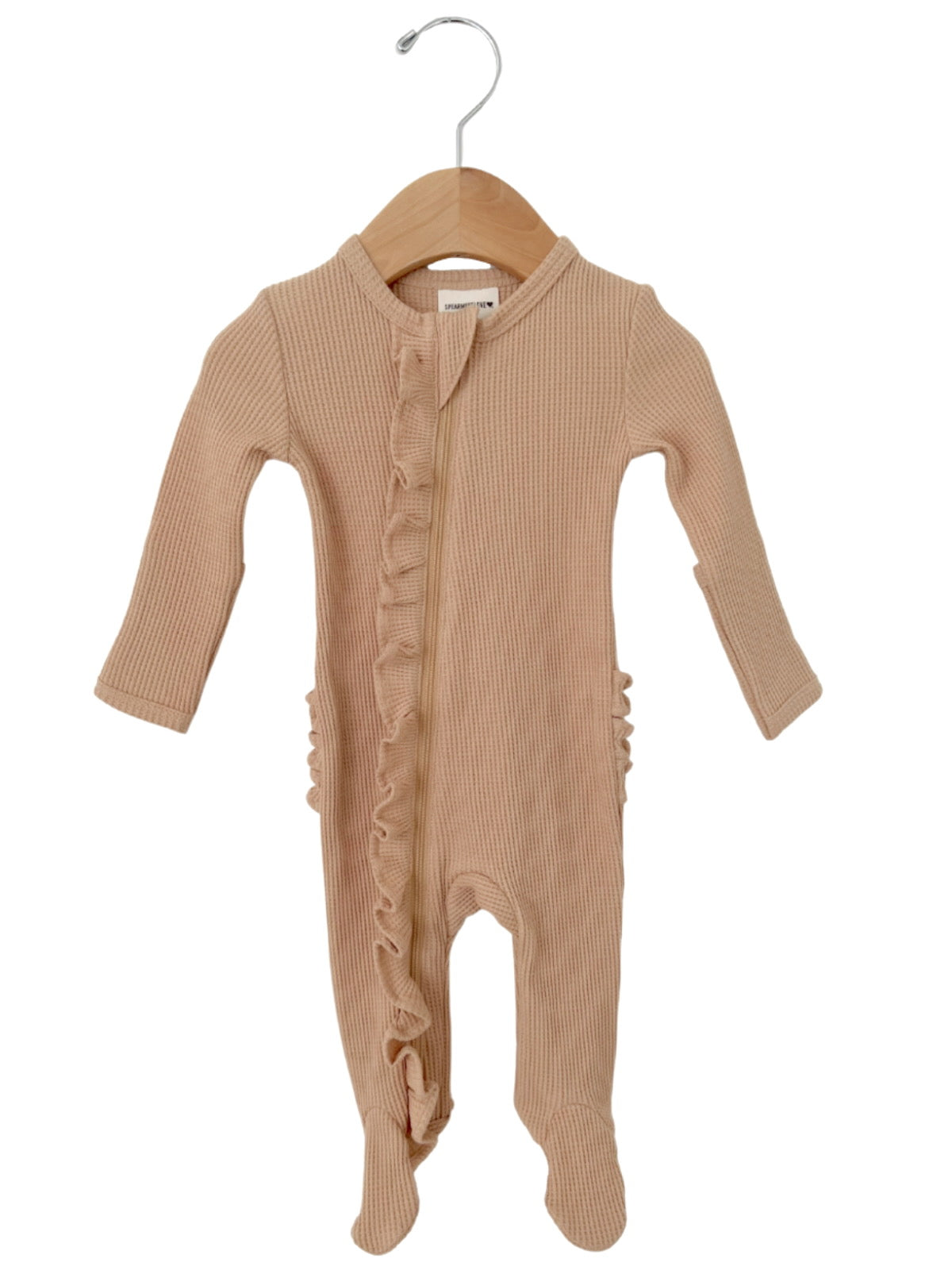Light beige baby onesie with ruffle detailing, featuring long sleeves and footed legs, displayed on a wooden hanger.
