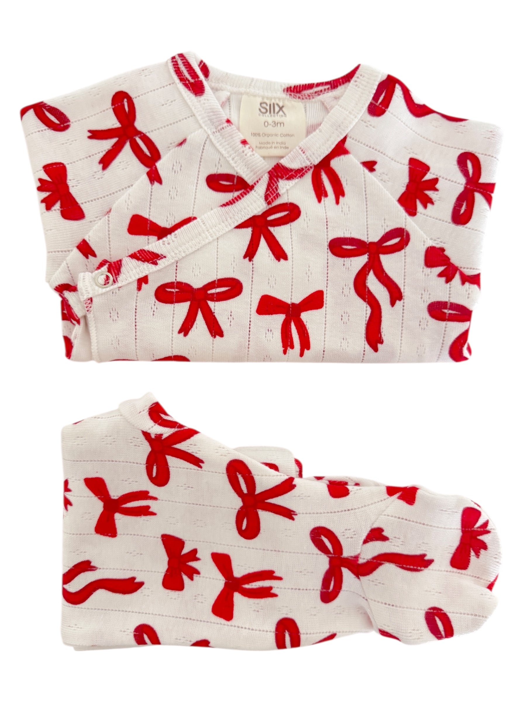 White infant outfit with red bow patterns, including a top and matching footie, made from 100% organic cotton.