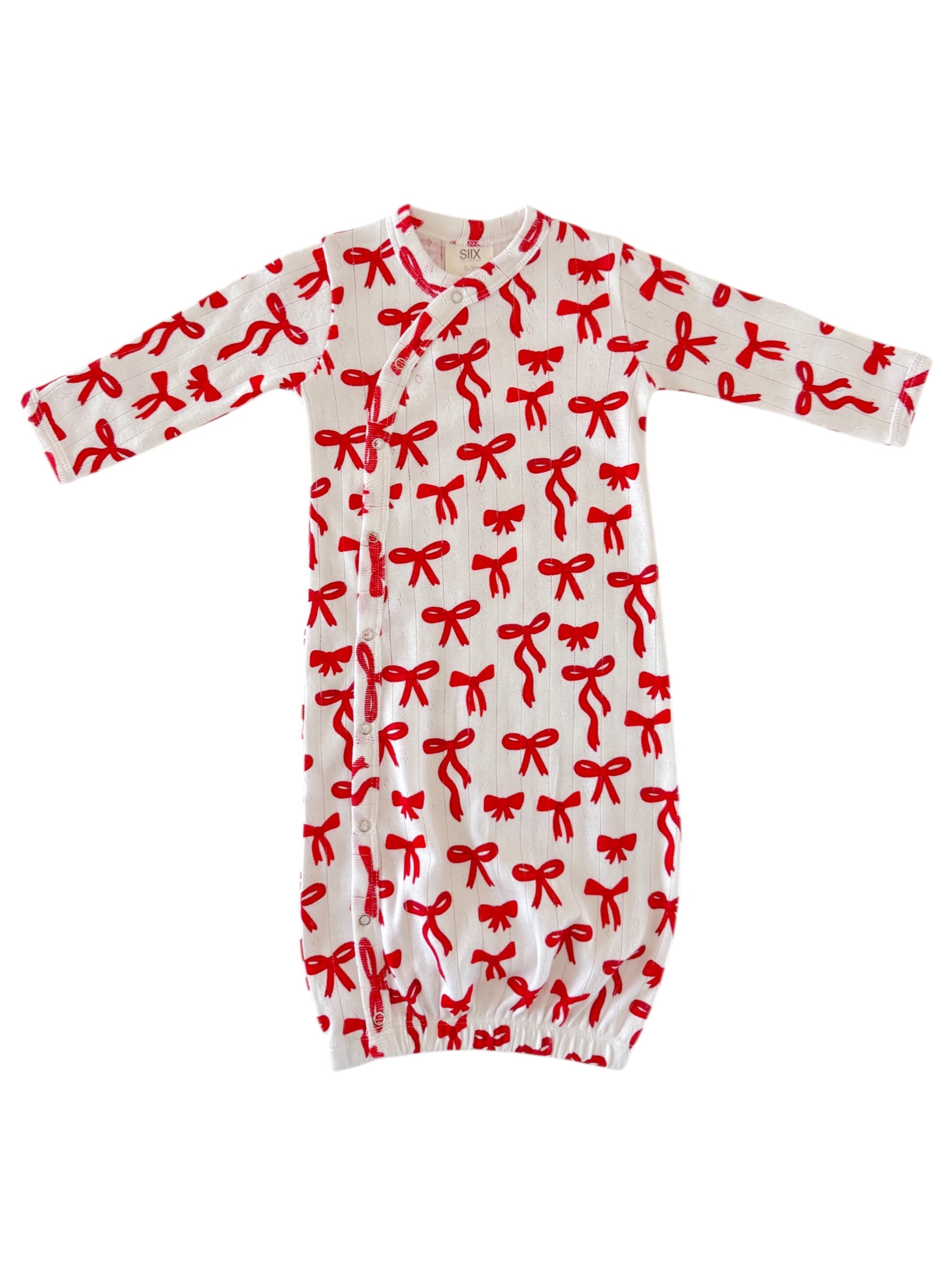 White baby gown with red bow print, featuring long sleeves and snap closures at the front.