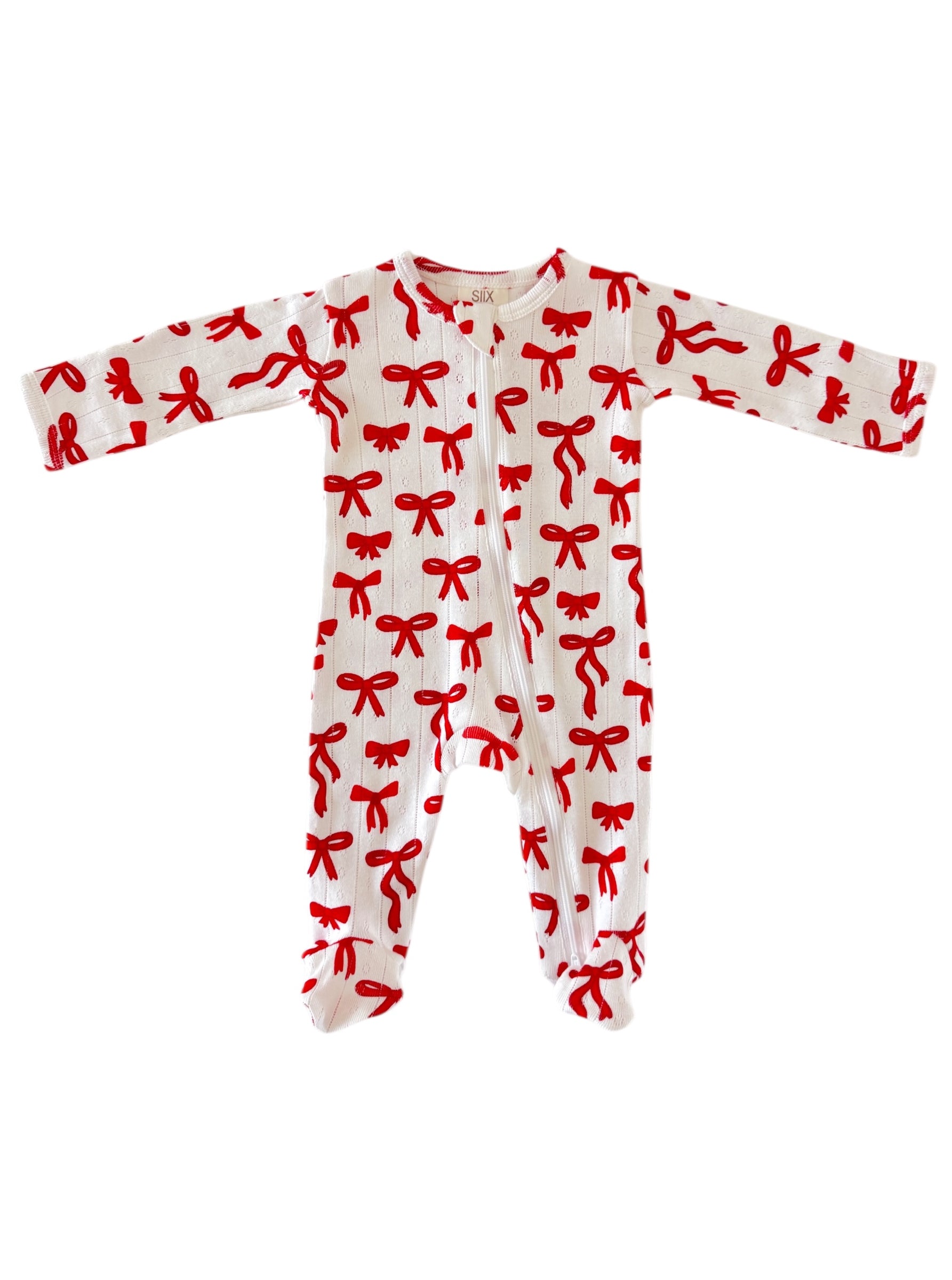 White baby onesie with red bow pattern and long sleeves, featuring a front zipper closure.