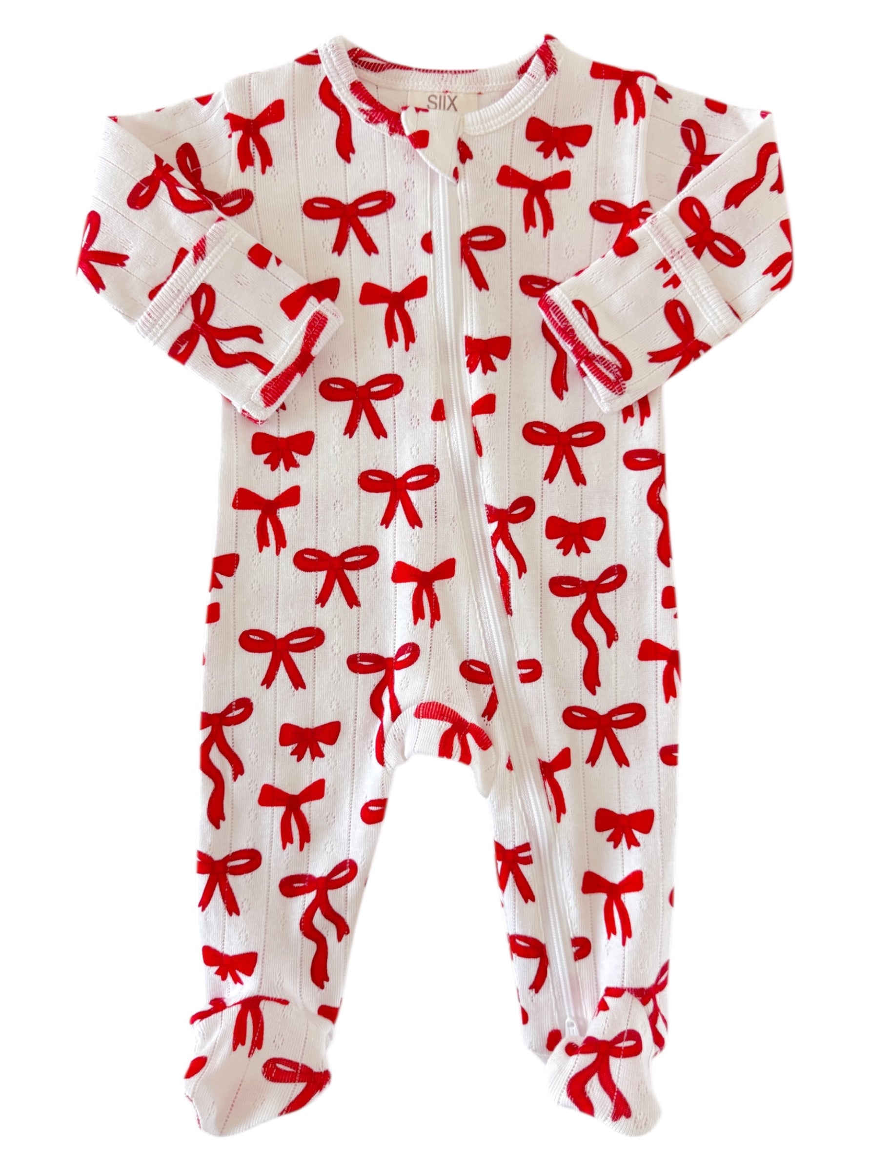 White baby onesie with red bow pattern and long sleeves, featuring snap buttons down the front.