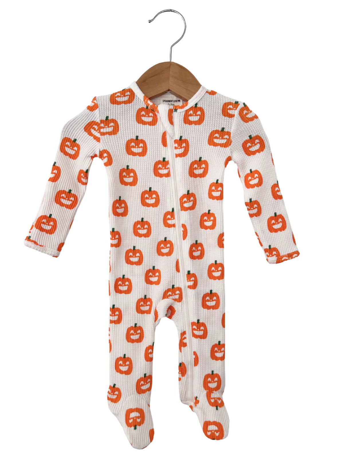 White baby onesie featuring a playful orange pumpkin pattern, hanging on a wooden hanger. Perfect for Halloween.