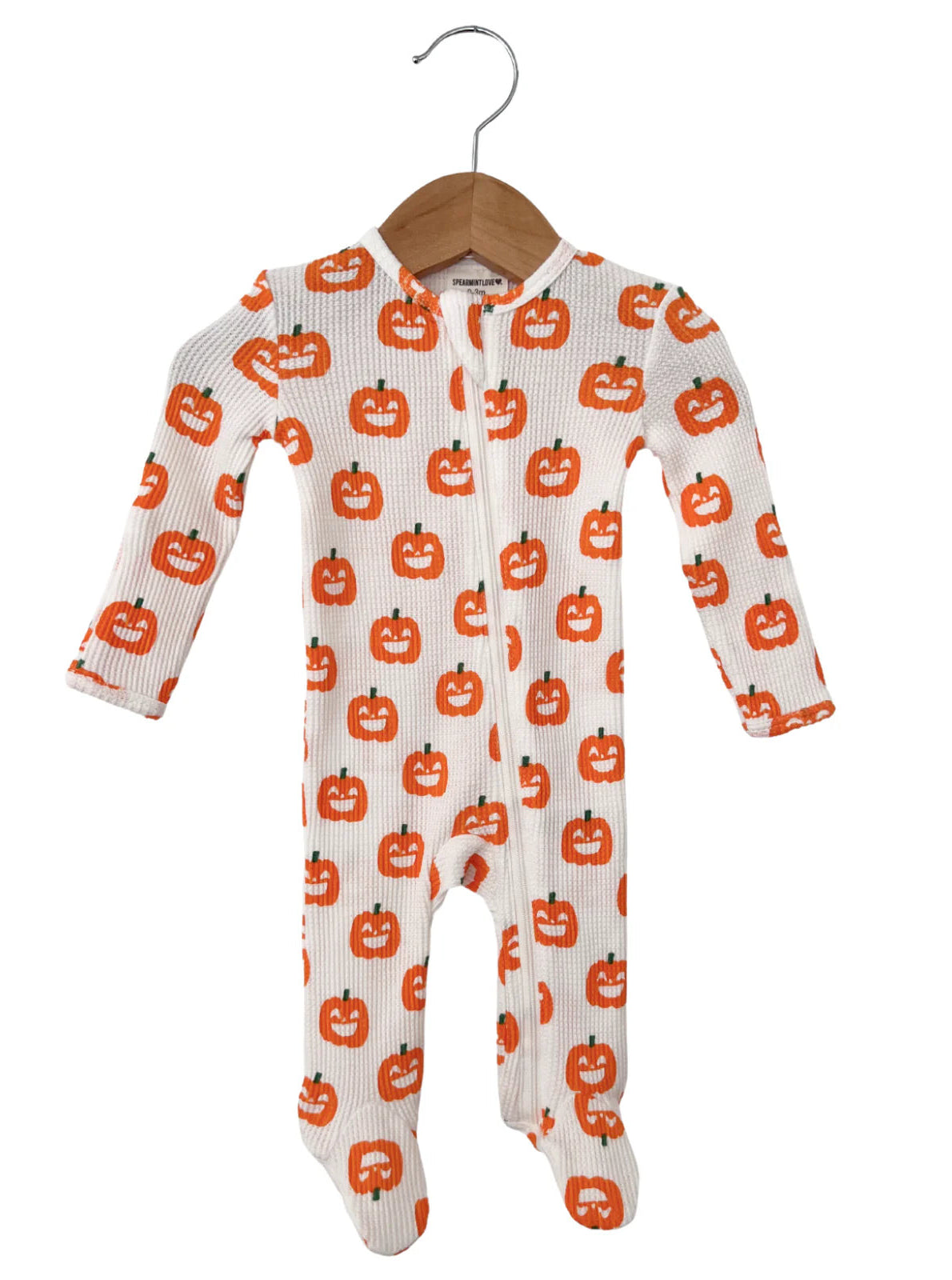 White baby onesie featuring a playful orange pumpkin pattern, hanging on a wooden hanger. Perfect for Halloween.