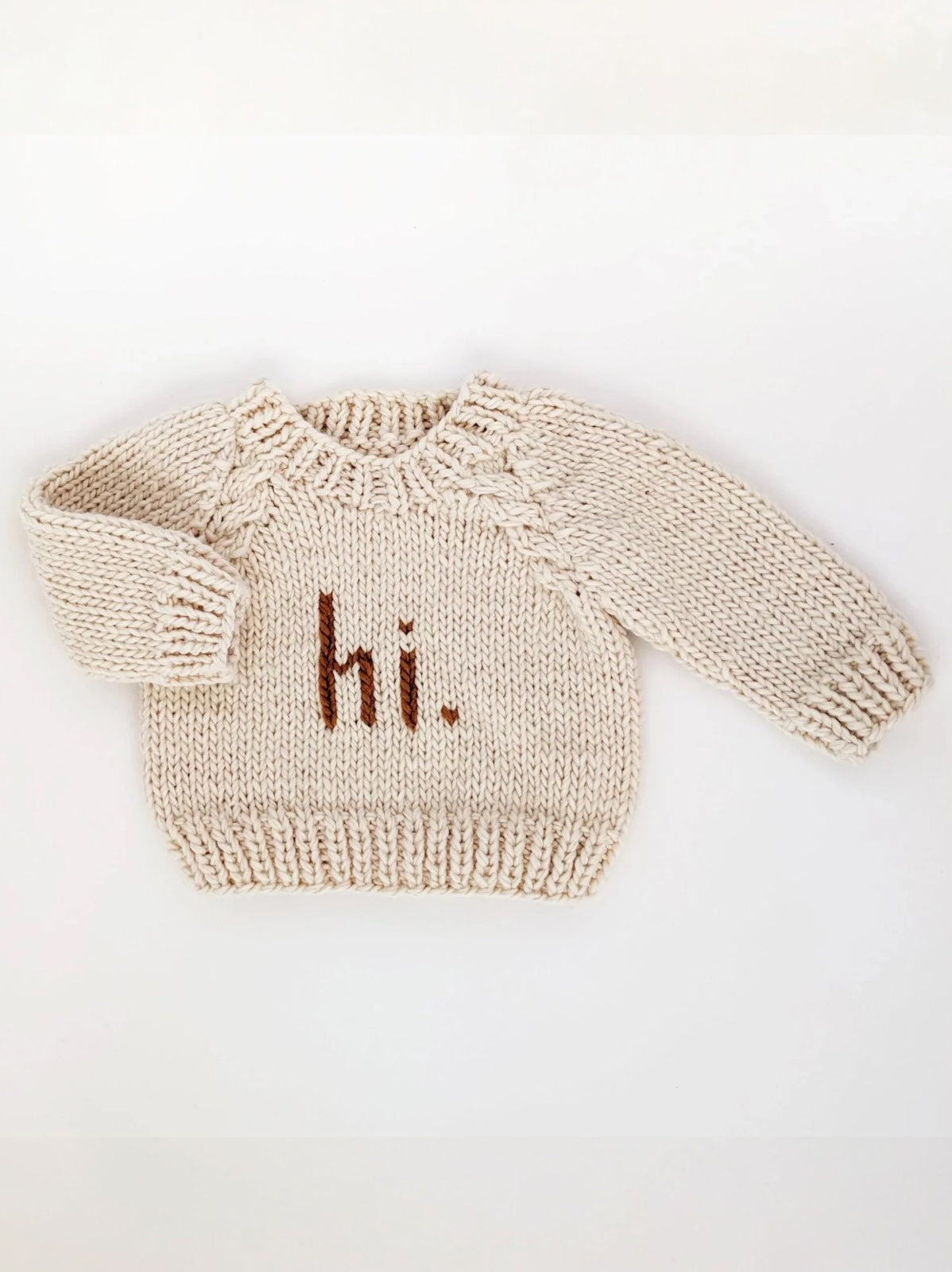 Cream-colored knit sweater with "hi." text displayed prominently on the front.