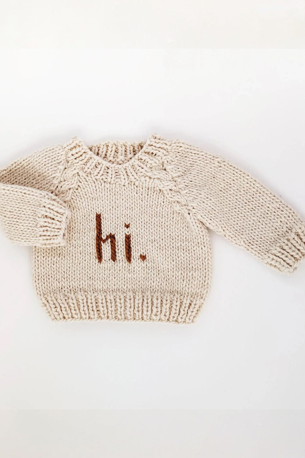 Cream-colored knit sweater with "hi." text displayed prominently on the front.