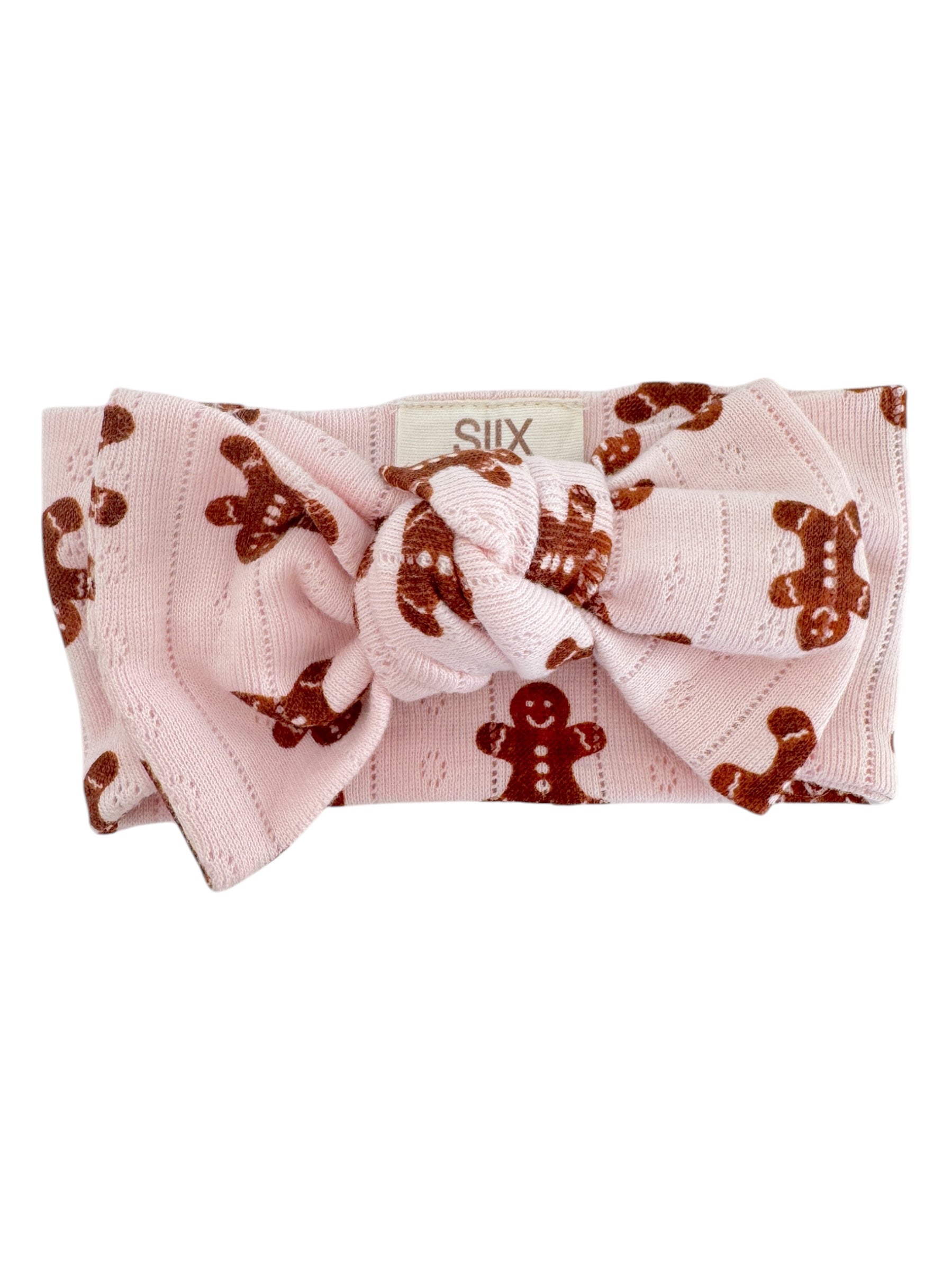 Pink headband with a large knot and gingerbread man pattern, perfect for festive occasions.