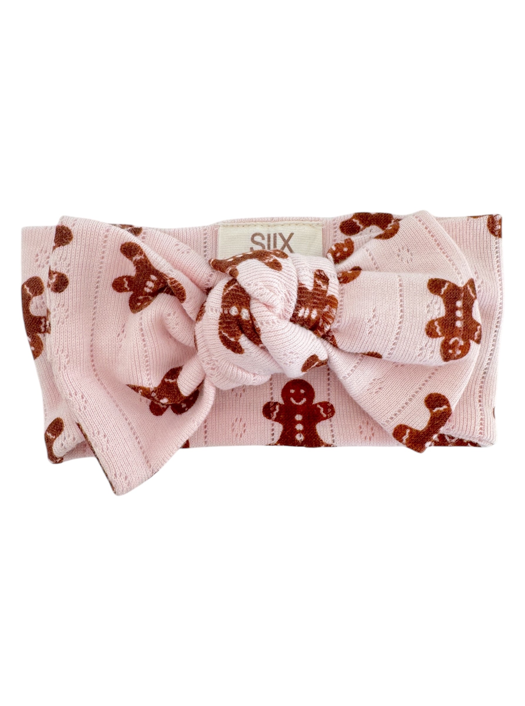 Pink headband with a large knot and gingerbread man pattern, perfect for festive occasions.