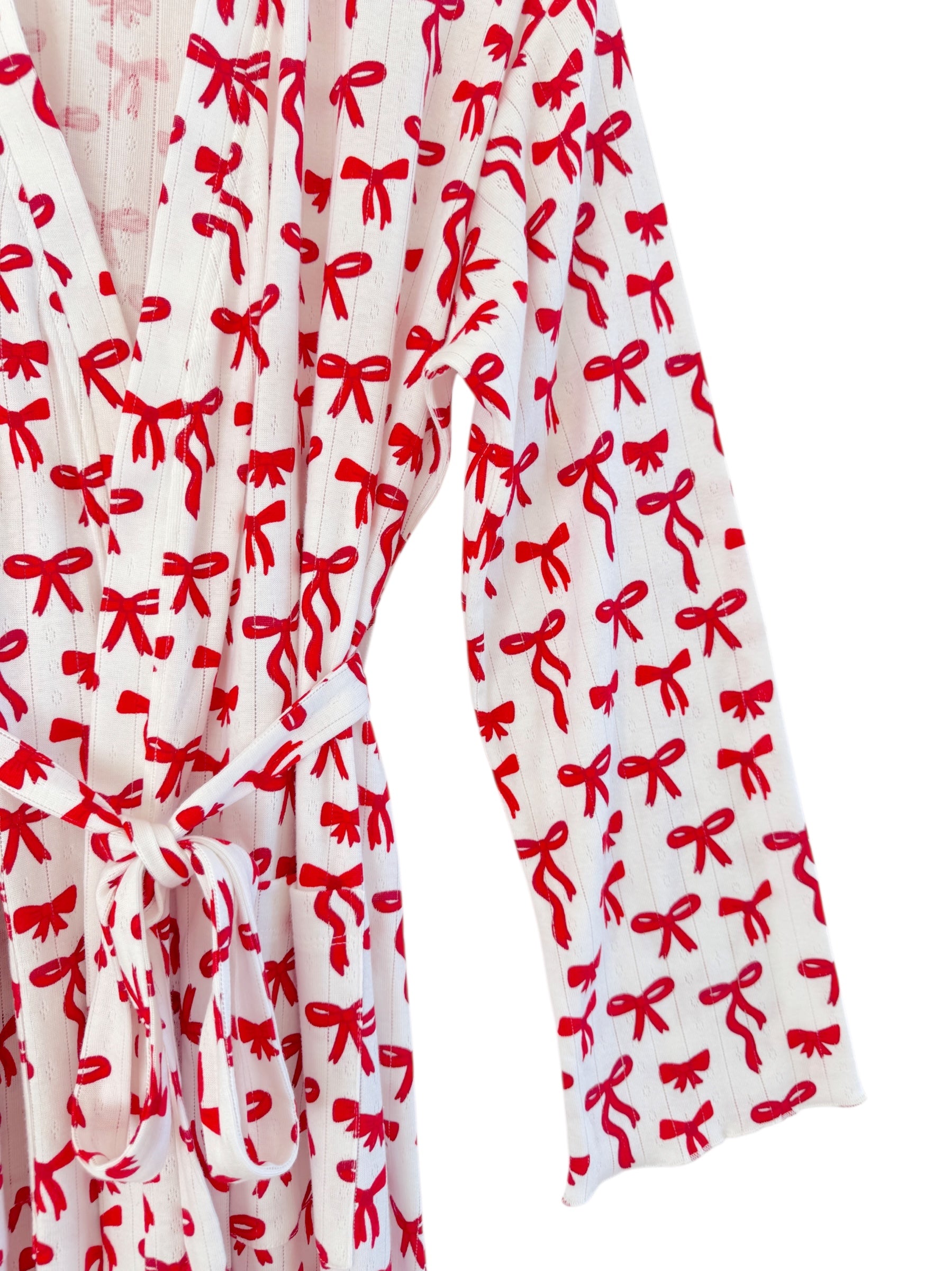 White robe with red bow pattern, featuring a tie at the waist and long sleeves.