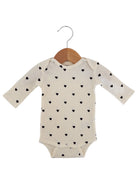Baby onesie with long sleeves, cream color, featuring a pattern of small black hearts.