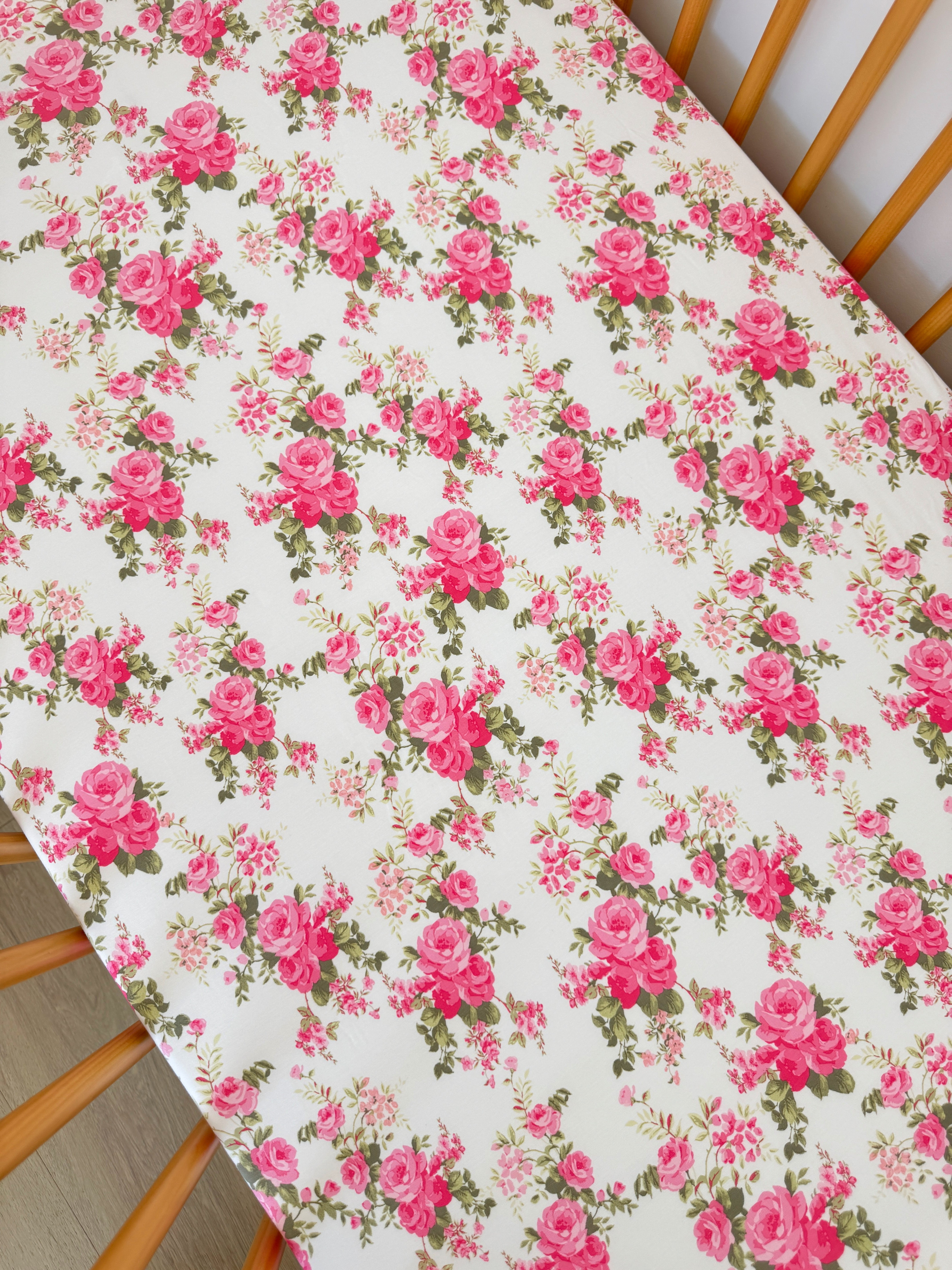 Floral tablecloth featuring pink roses and greenery on a light background.