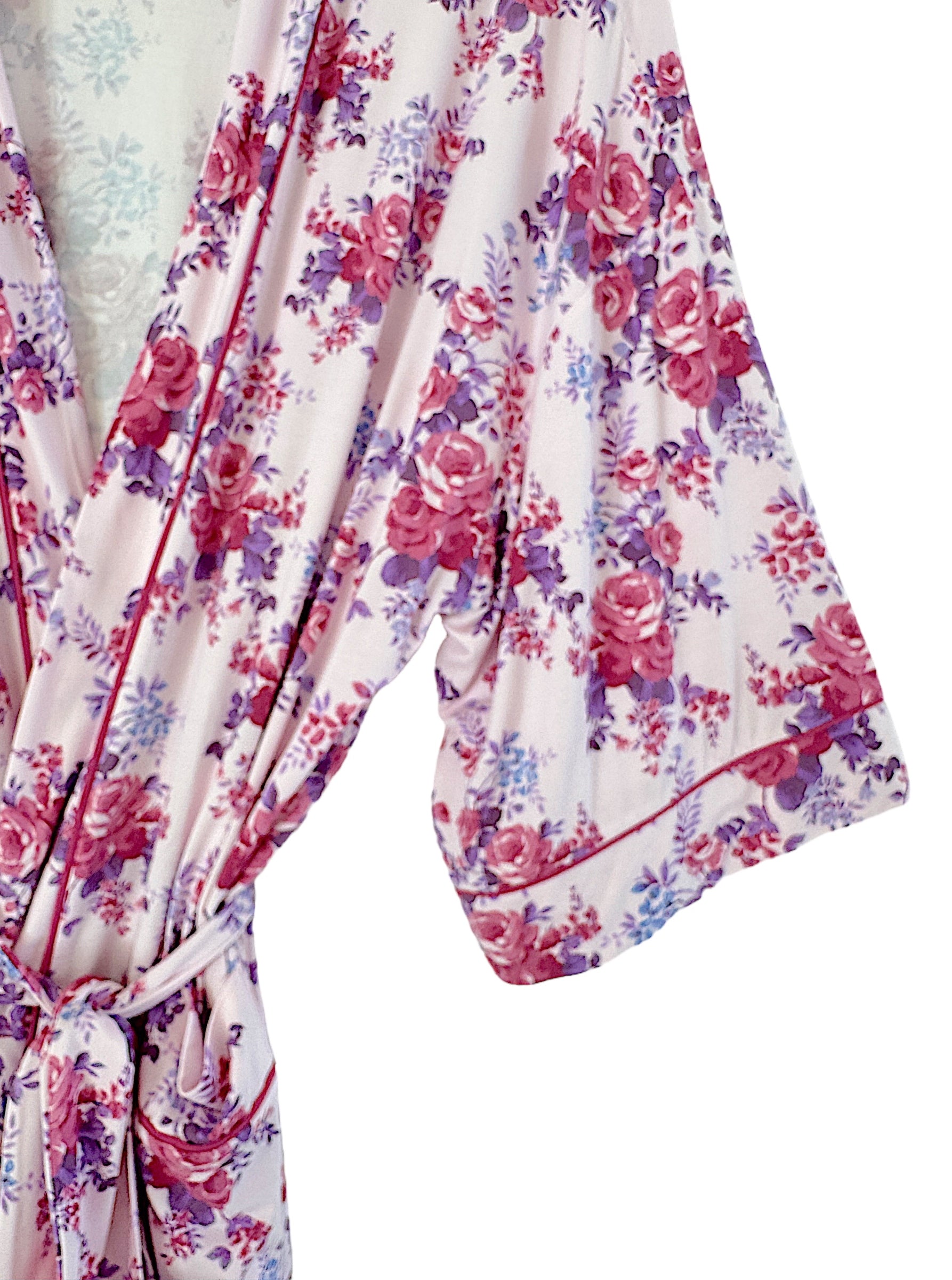 Floral-patterned robe in soft fabric, featuring pink, purple, and white hues, with a tie closure and flowing sleeves.