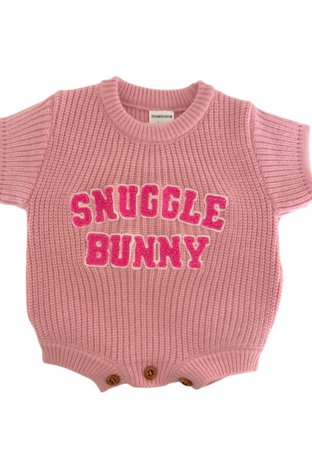 Pink knit baby onesie with "Snuggle Bunny" text in bold, playful letters. Ideal for cozy occasions.