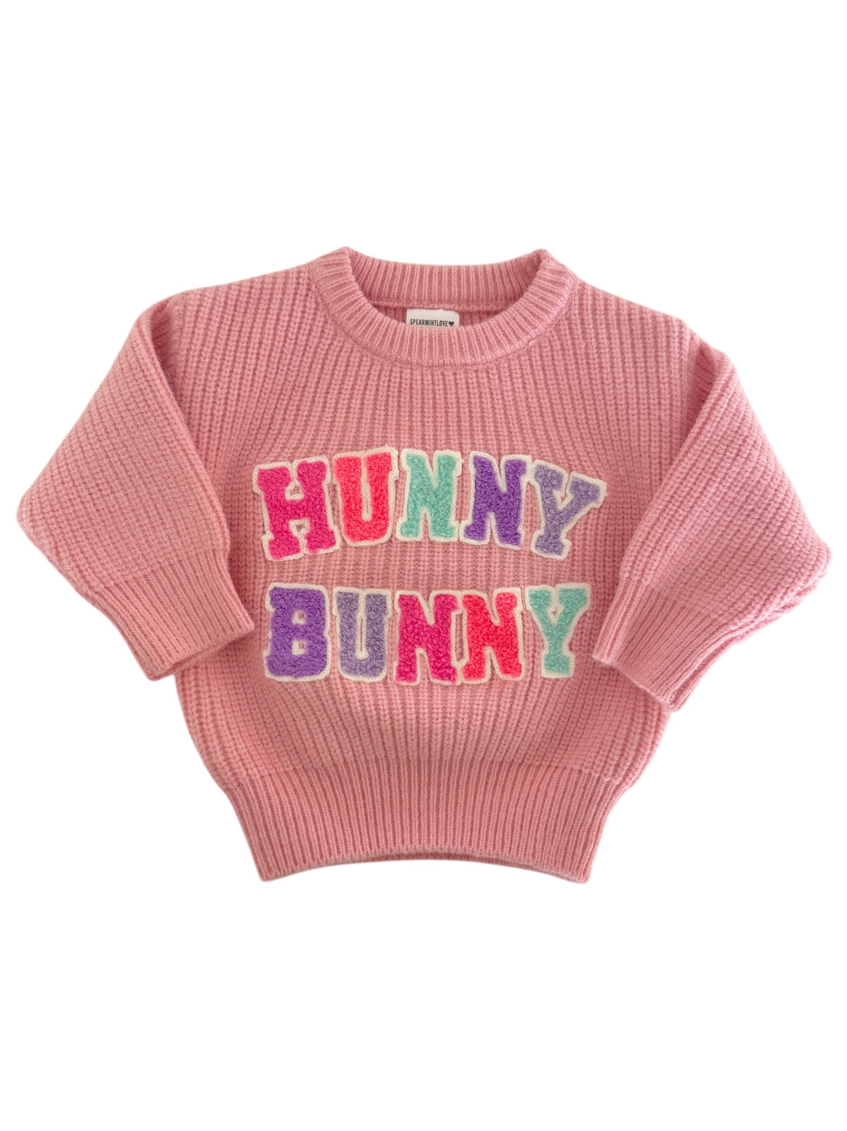 Pink sweater with "HUNNY BUNNY" in colorful letters on the front, featuring a ribbed design and short sleeves.