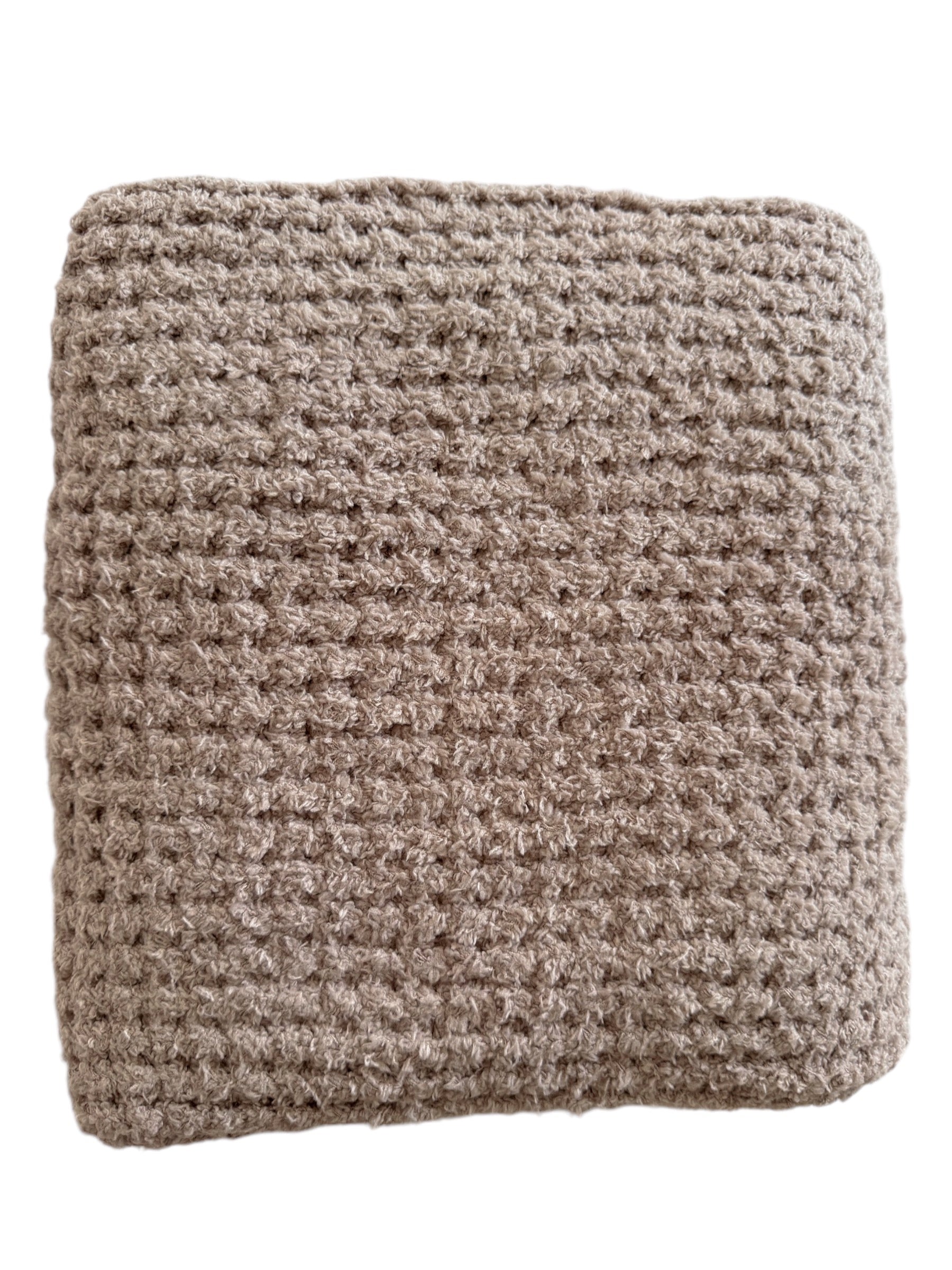 A neatly folded, textured beige blanket with a cozy woven pattern.