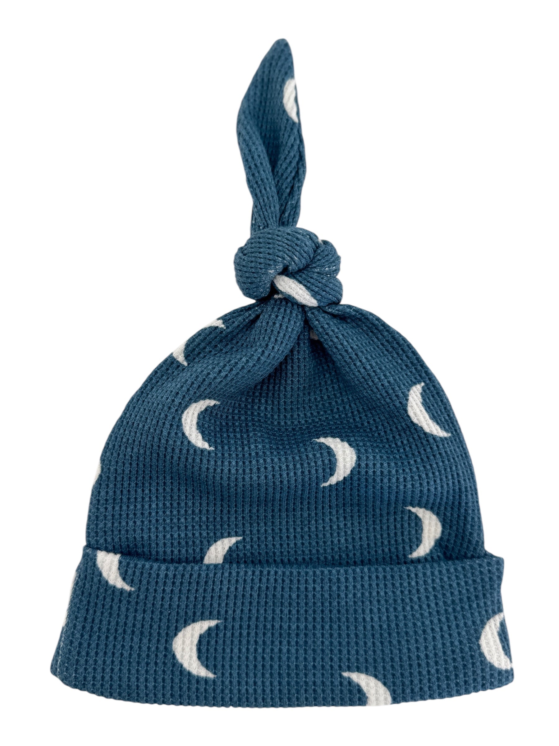Blue knit hat with crescent moon patterns and a knotted top, suitable for infants.
