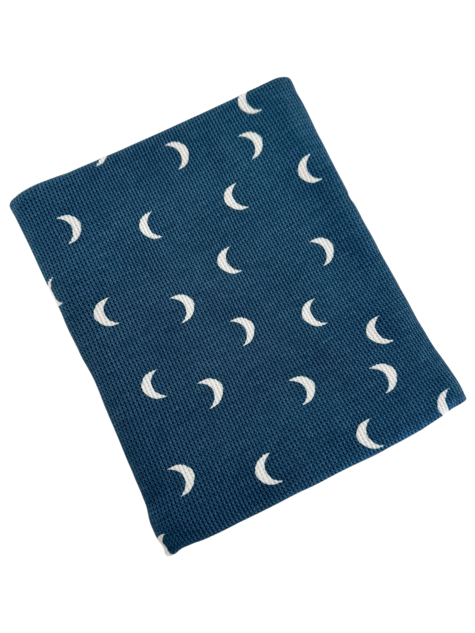 Blue blanket featuring a pattern of white crescent moons. Perfect for adding a cozy touch to any space.