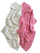 Two textured blankets, one white and one pink, overlapping on a white background.