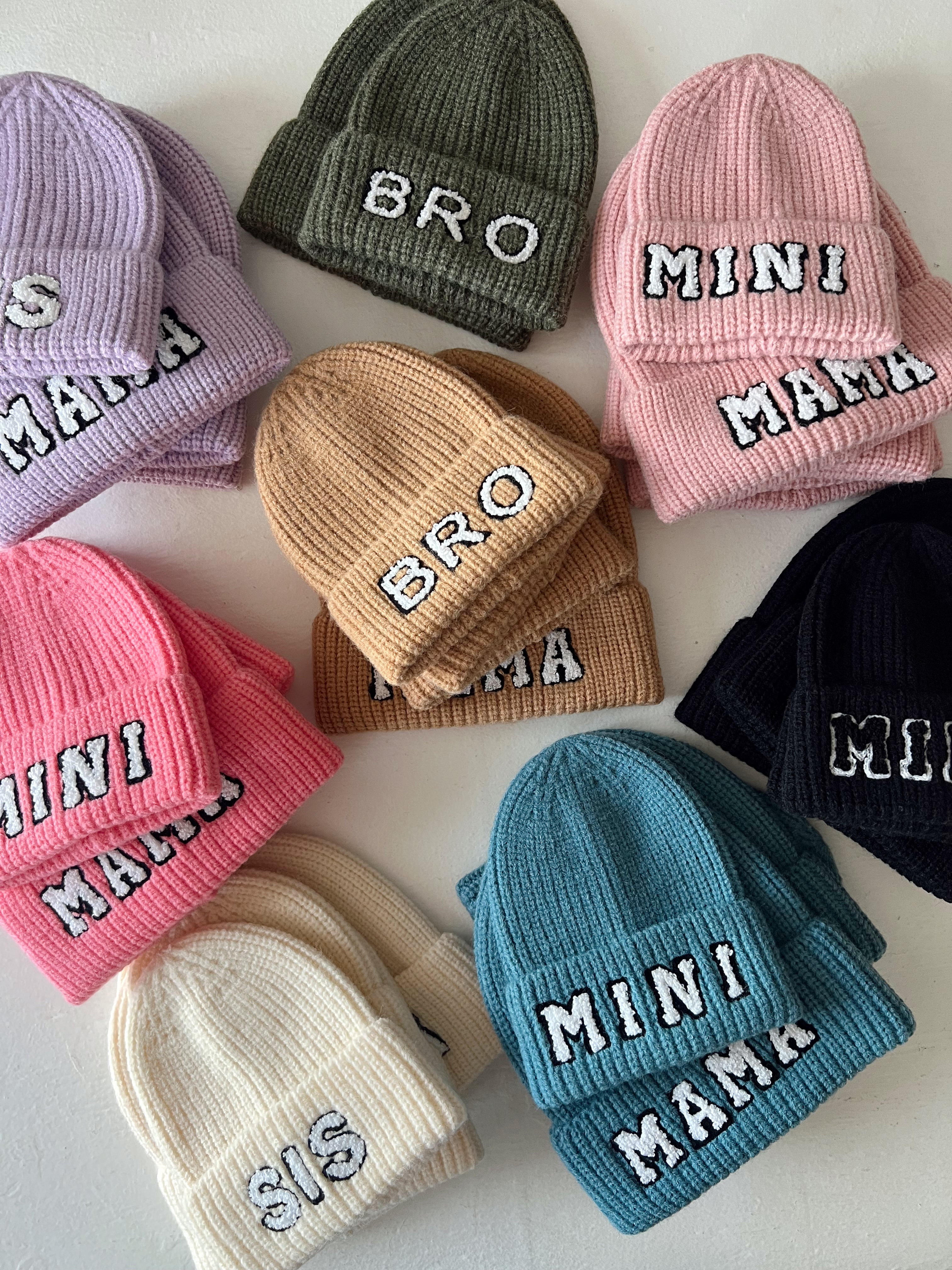 Colorful beanies with text labels: "BRO," "MINI MAMA," "SIS," in various styles and colors.